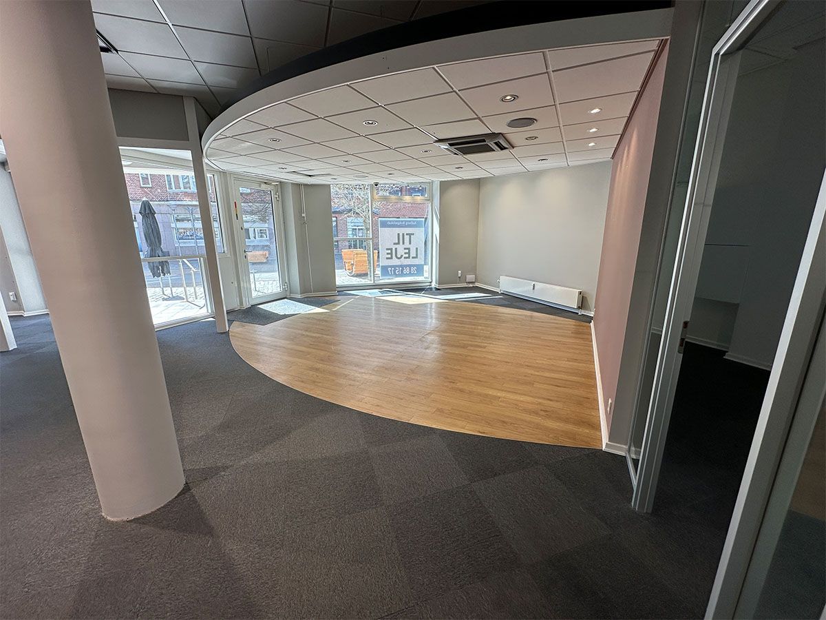 Erhvervslokale til leje med store glasvinduer og åbne områder, lys og moderne gulvbelægning, og luftkøler på loftet