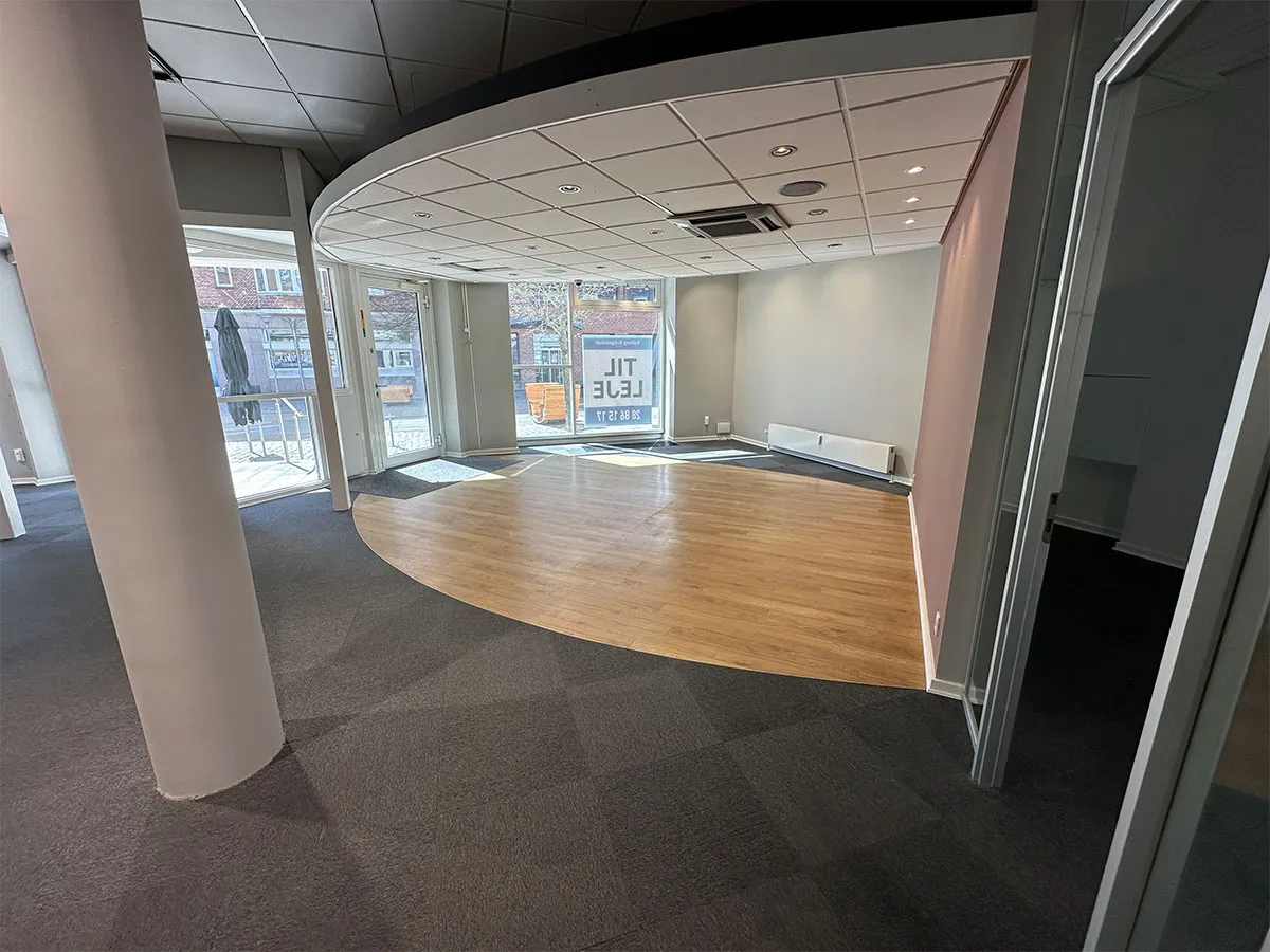 Erhvervslokale til leje med store glasvinduer og åbne områder, lys og moderne gulvbelægning, og luftkøler på loftet
