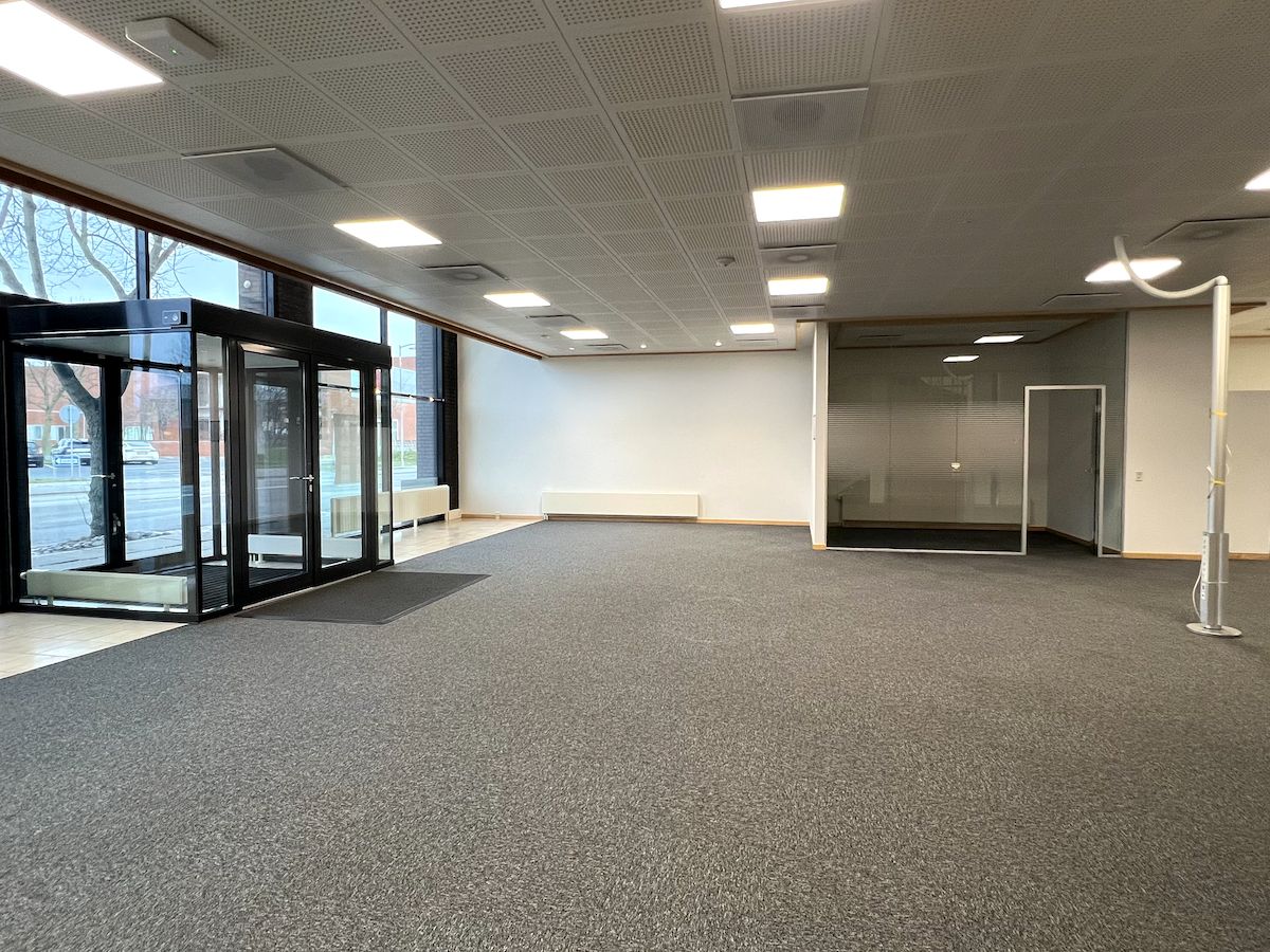 En tom kontor- og mødelokation med lyse, hvide vægge, glasruder og moderne indretning i Frederikshavn