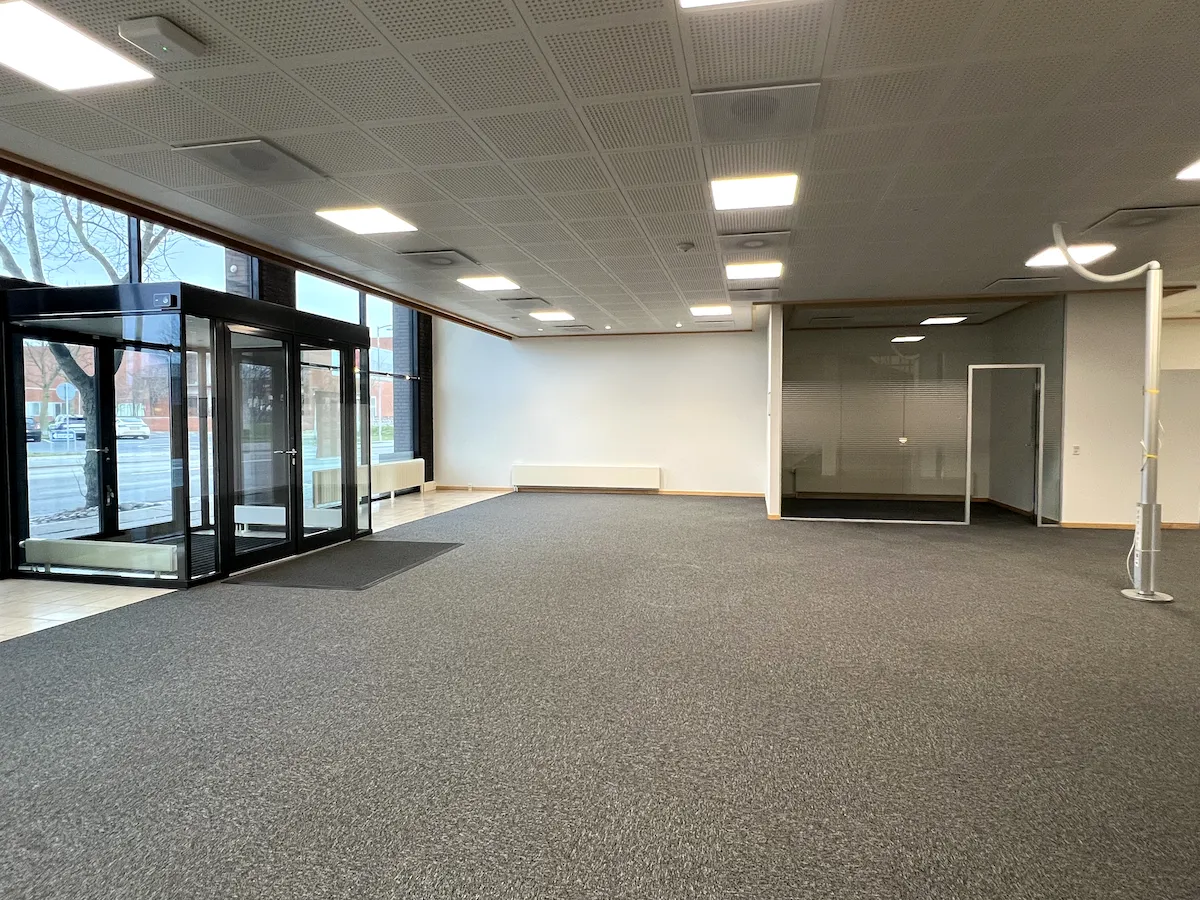 En tom kontor- og mødelokation med lyse, hvide vægge, glasruder og moderne indretning i Frederikshavn