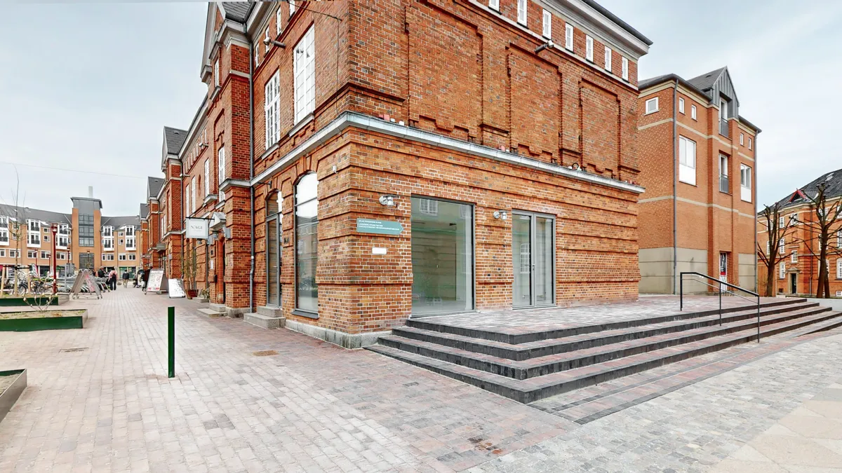 Indbydende og velbeliggende erhvervslejemål på Østerfælled Torv 14A, 2100 København Ø. Bygningen er bygget i rød mursten og har lyseruderede vinduer