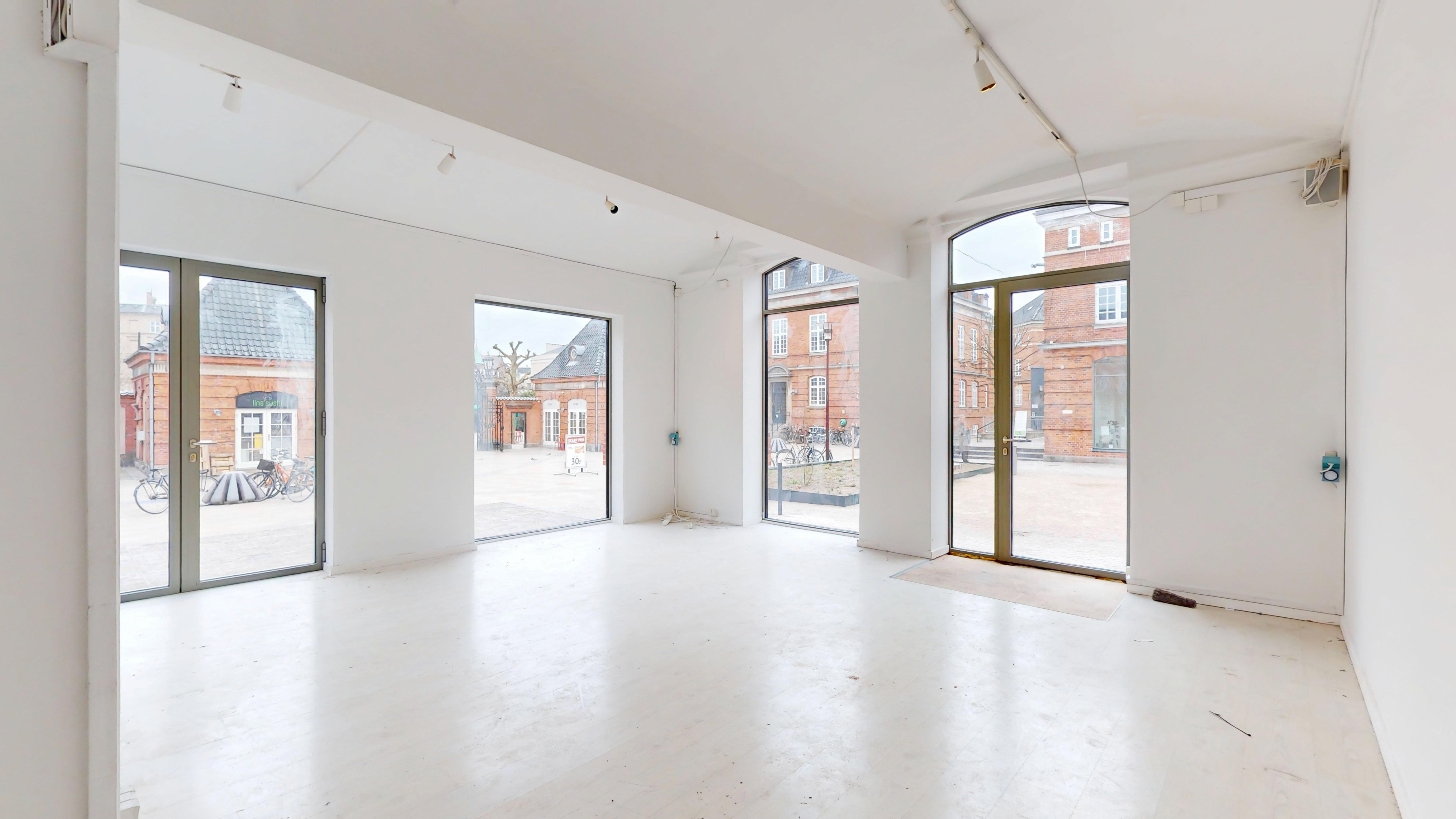 Indbydende lejemål på Østerfælled Torv med store glasvinduer og hvidt interiør, som er renoveret og klar til brug