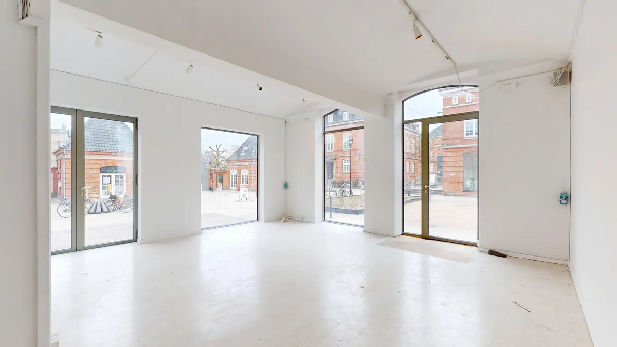 Indbydende lejemål på Østerfælled Torv med store glasvinduer og hvidt interiør, som er renoveret og klar til brug