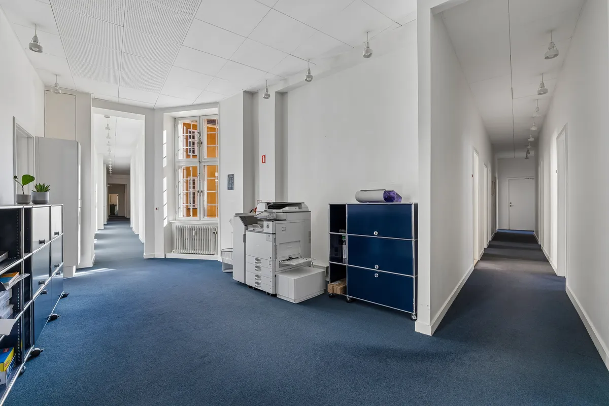 Kontor til leje på Ny Vestergade 17 i København med lyse, neutrale farver og moderne møbler, inklusive printere og højre filehylde.