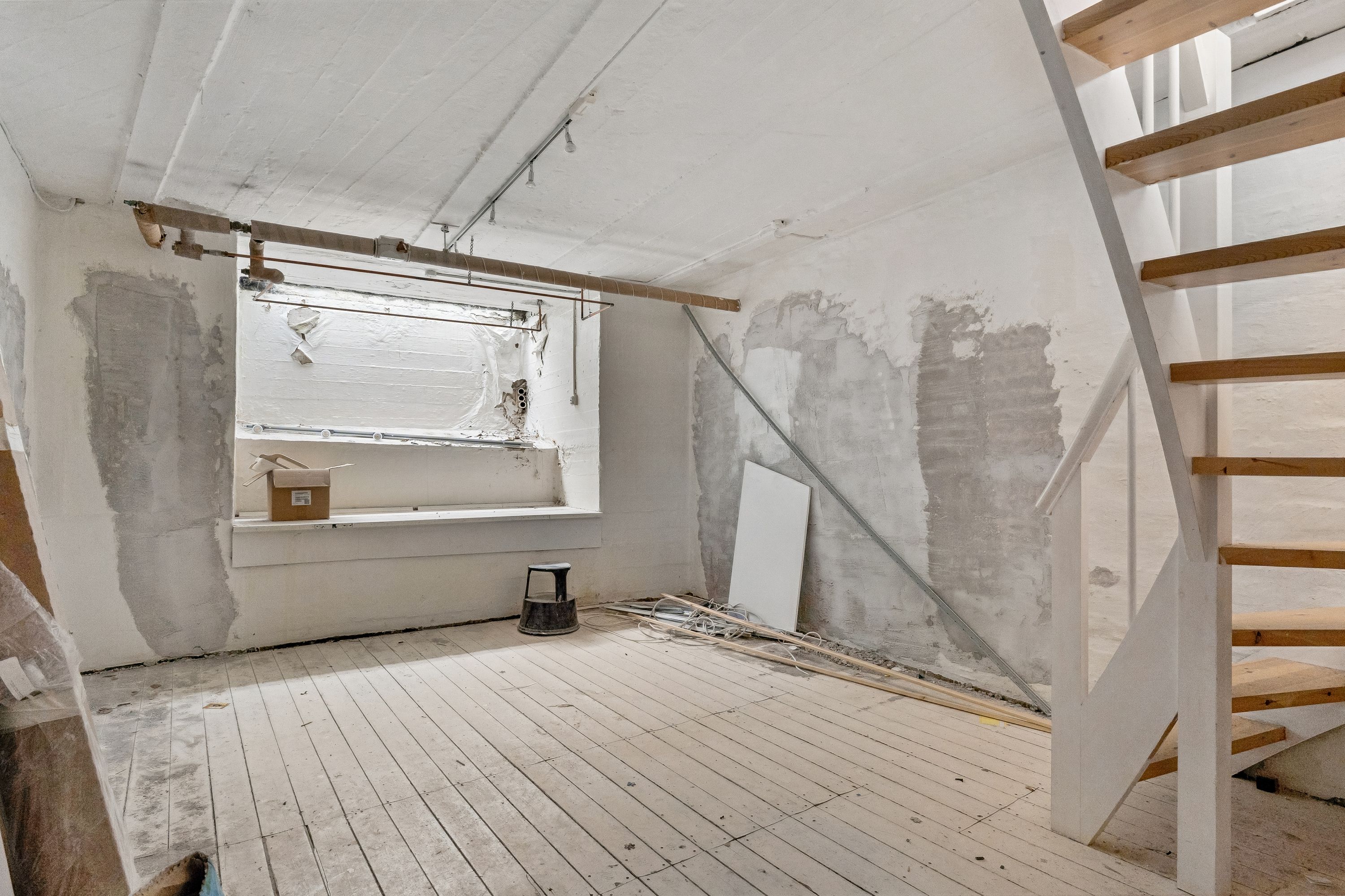 Udenforsiden af en lejlighed, der er under renovering, med en stol, en kasse og et trinvist trætrappe, der fører til stueetagen