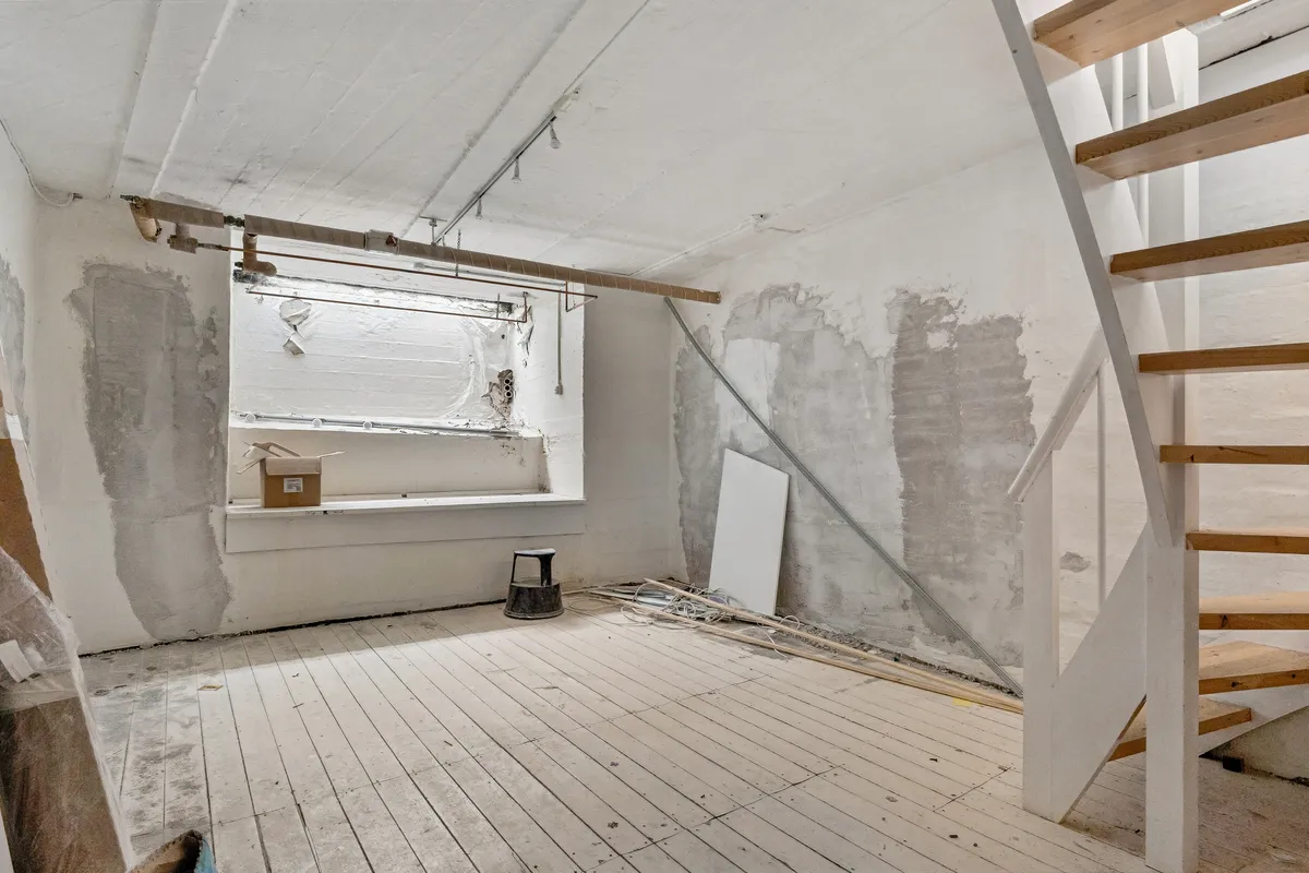 Udenforsiden af en lejlighed, der er under renovering, med en stol, en kasse og et trinvist trætrappe, der fører til stueetagen