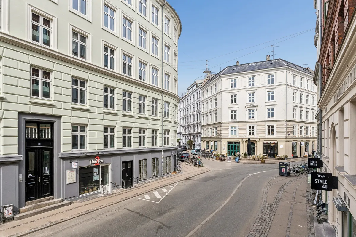 Butik med glasvinduer og skilte på hjørnet af Birkegade og Elmegade i København N, med tomme gader og cykler parkeret foran
