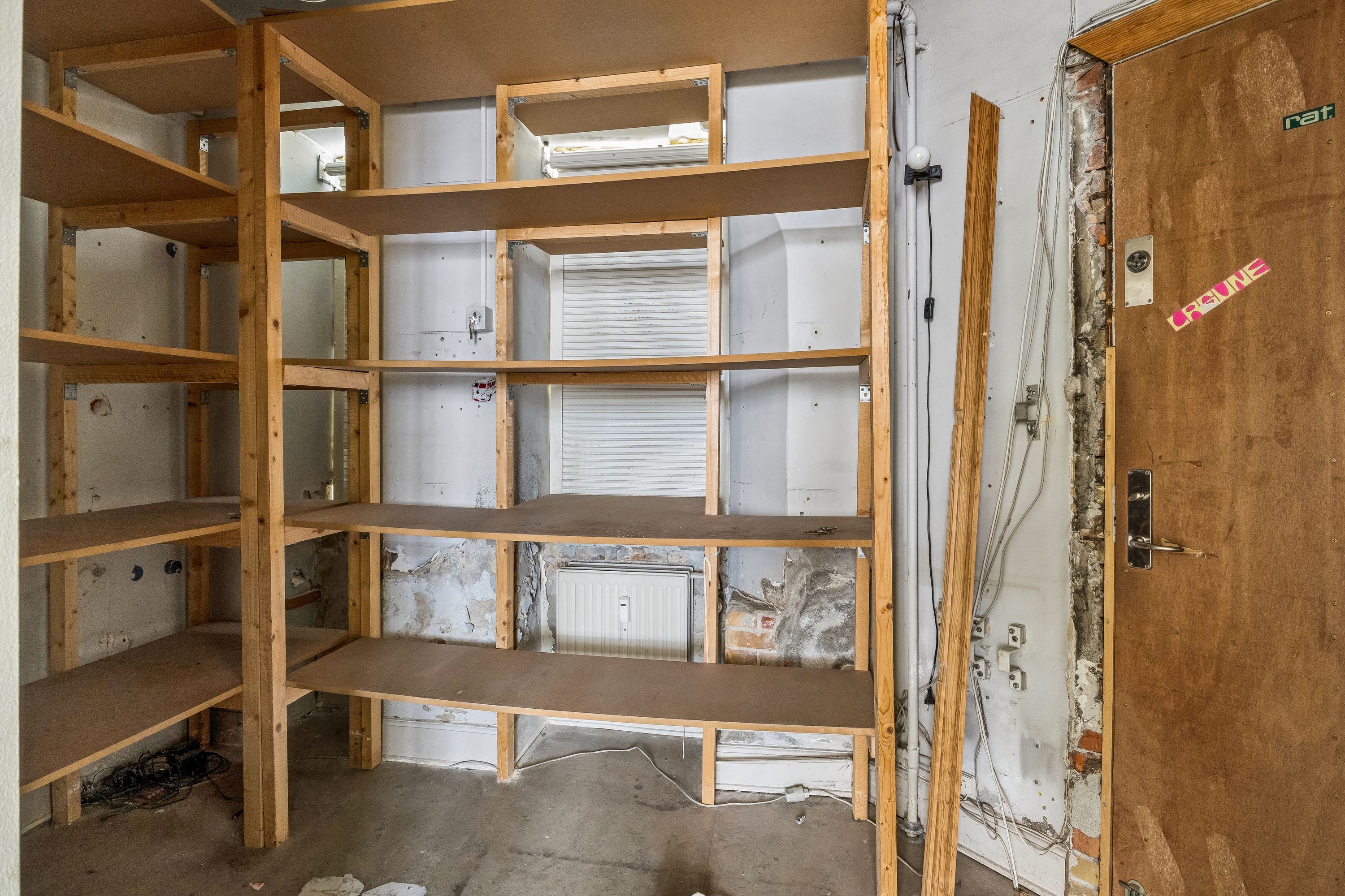 Lejlighed med flere hylder og ledningsforløb i gården i Nørrebro med åbne døre og lysepunkter