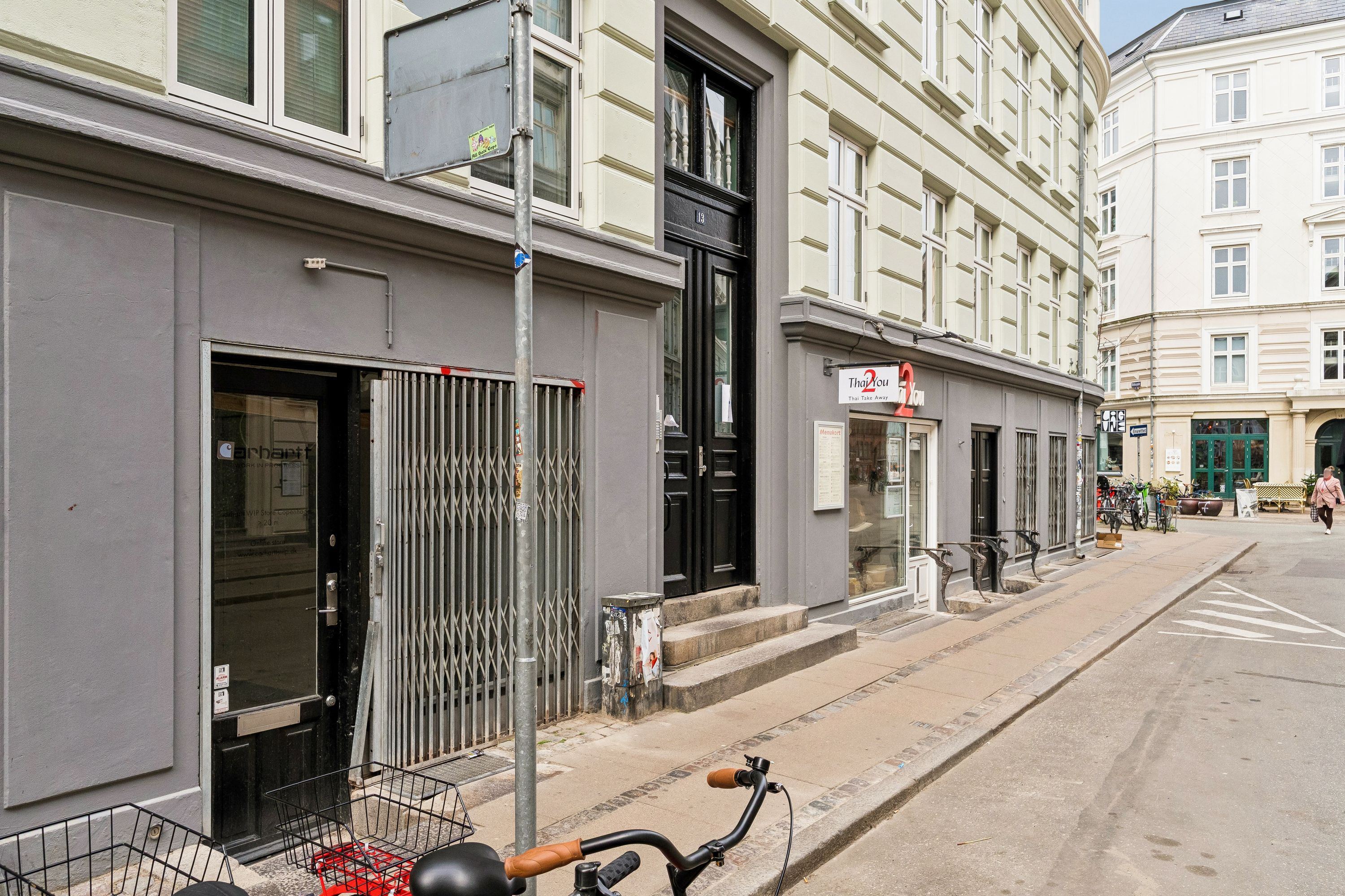 Butik til leje på Elmegade 13 i København. Cykelparkeret foran butikken og lukket med stige. Butik med udstillingsvindue og tekst på døren.