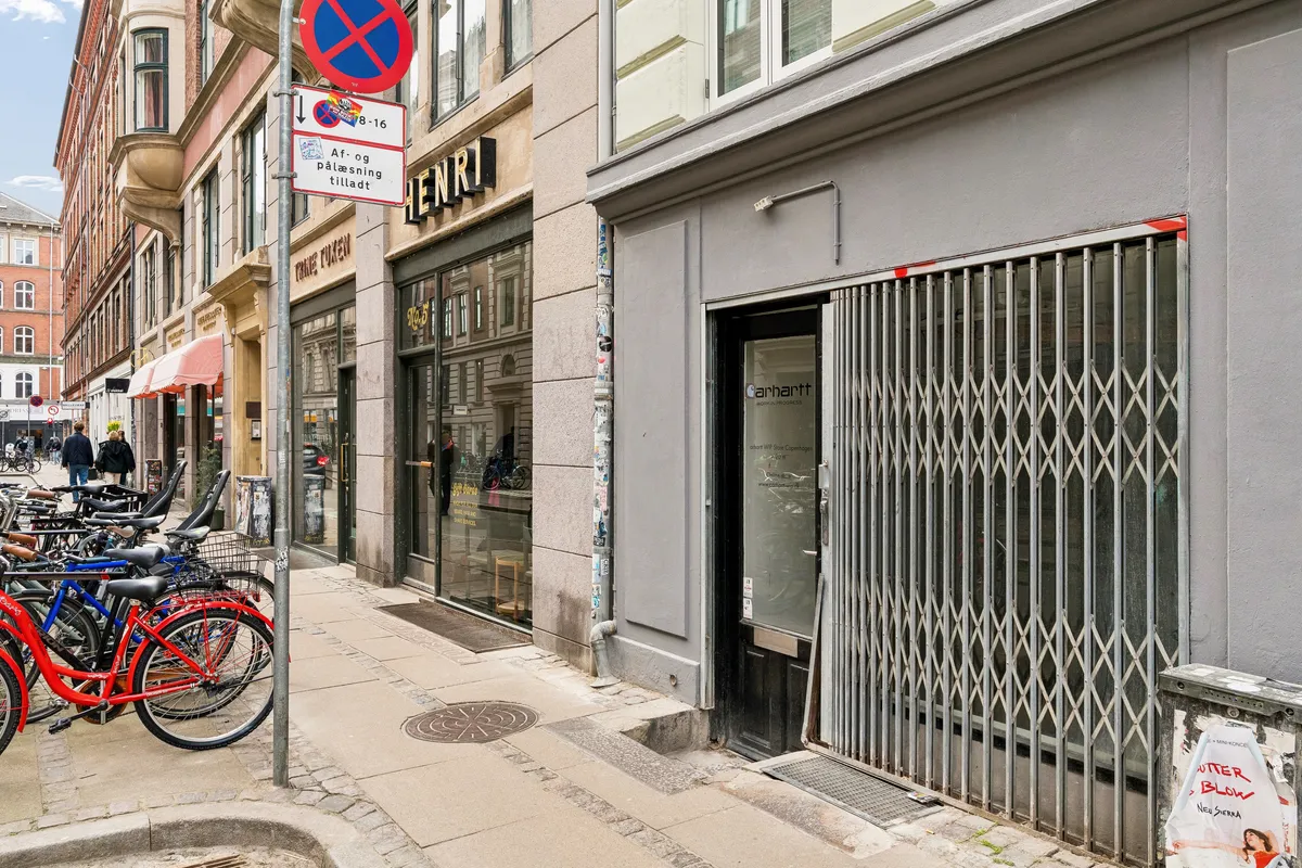 Gade med cykelstativer og åbne butiksdøre i København. Strøget er i Nørrebro og er kendt for sit levende handelsmiljø med trendy butikker.