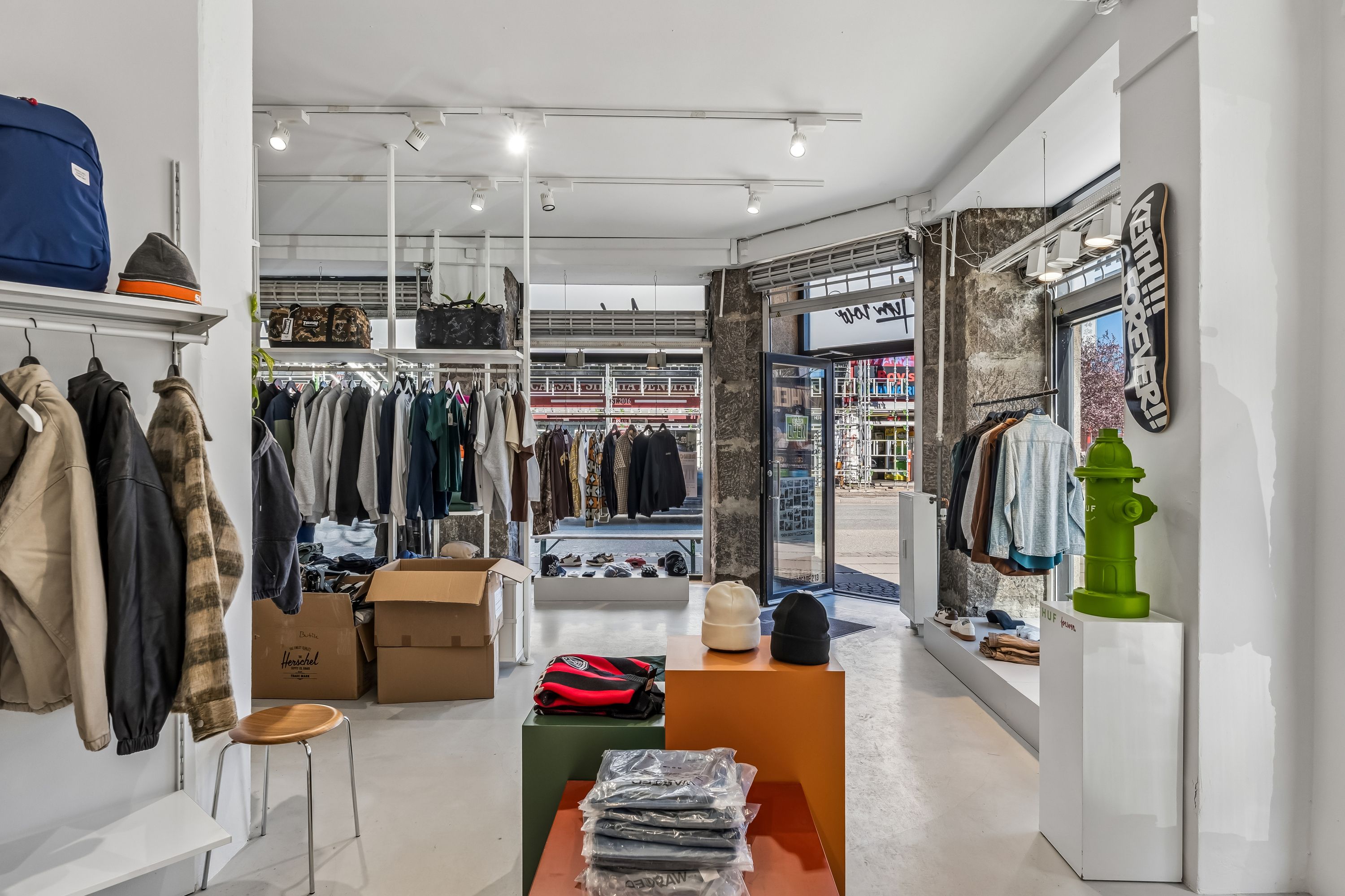 En butik med tøj og sko samt møbler og sportsudstyr i et lyst og velorganiseret interiør med grønt vandhane og lysekroner i loftet