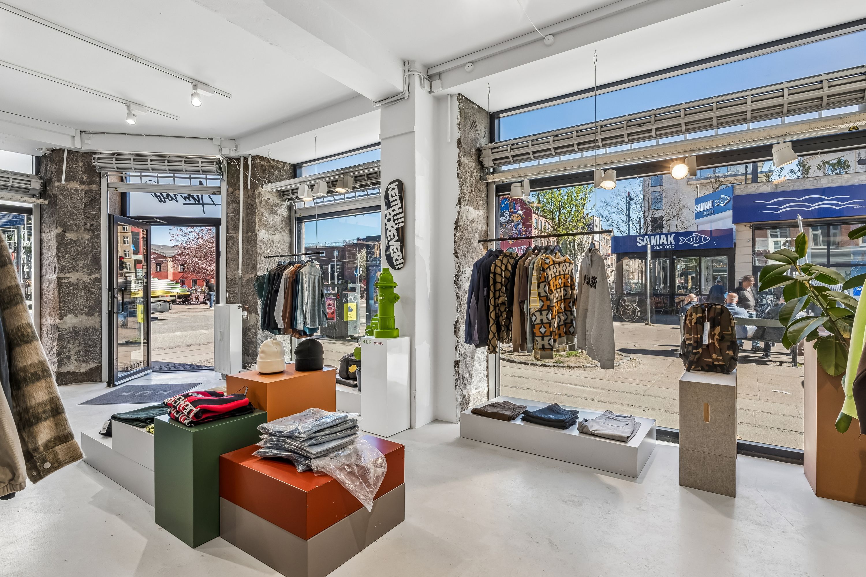 Moderne butik med tøj og tilbehør udstillet i skarpe farver og lyse vinduer på Nørrebrogade 213. Butikken er veludstyret med nyttige højhynder og lyse punkter på loftet.