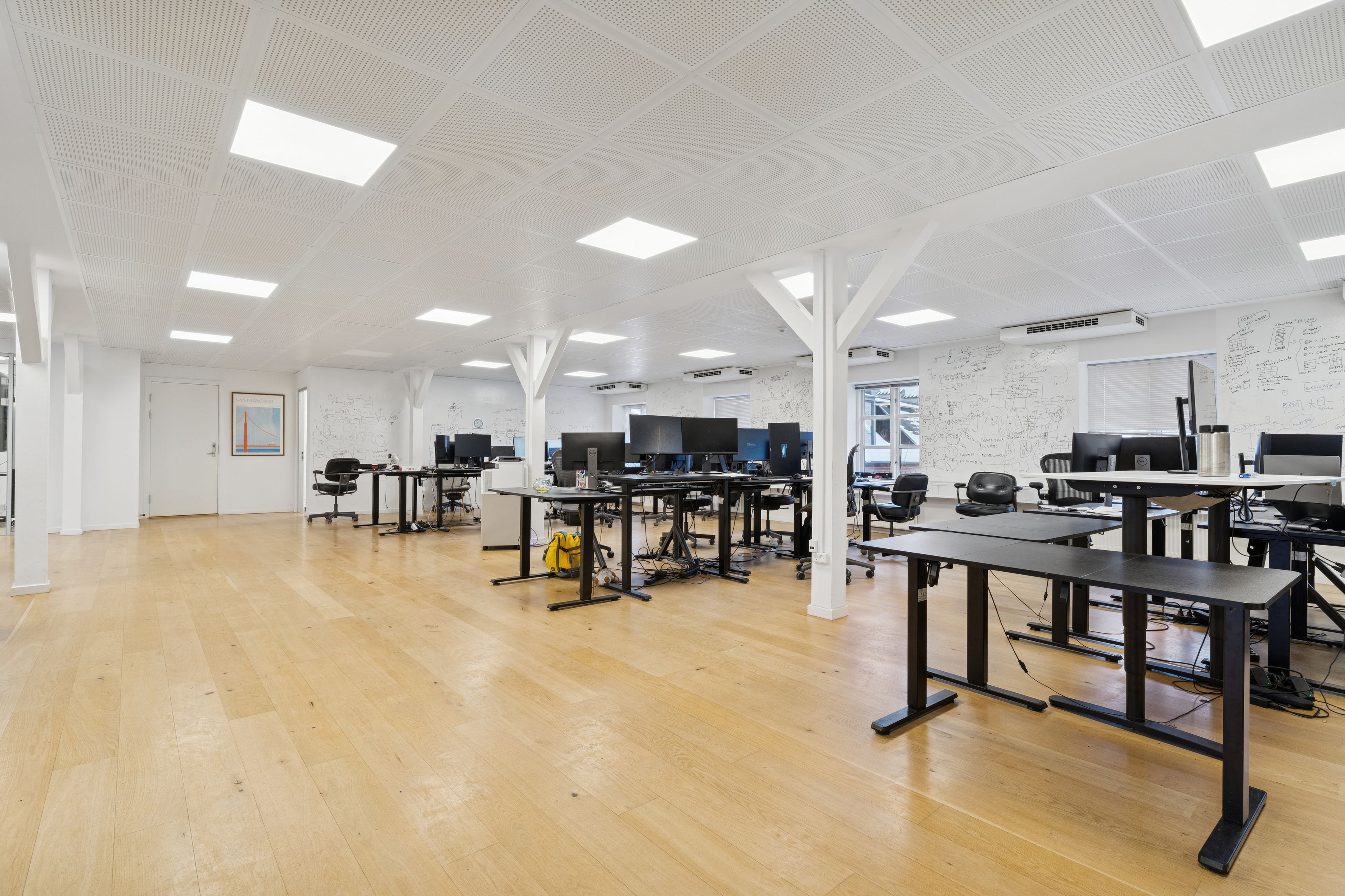 Kontorlejemål med moderne møbler og højt til loftet i Københavns Indre By. Billeder af ergonomiske skriveborde, computere og skrivebordslamper.