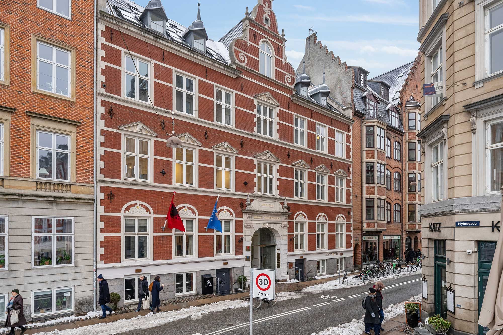 Kontorlejemål på Frederiksholms Kanal 4B, 5. sal, 1220 København K med 30 km/t hastighedsgrænse, røde mursten og røde flag, smukt bygningsværk, folk vandrer og gå på snedækket, møder nye venner.