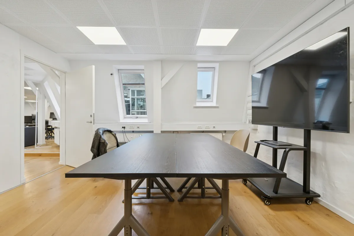 Kontorrum med lyse loftsrum, hvidt interiør og trægulv, møbler og moderne teknologi. Lejligheden er tæt på Gammel Strand metro, og der er gode kommunikationsforbindelser til centrum.