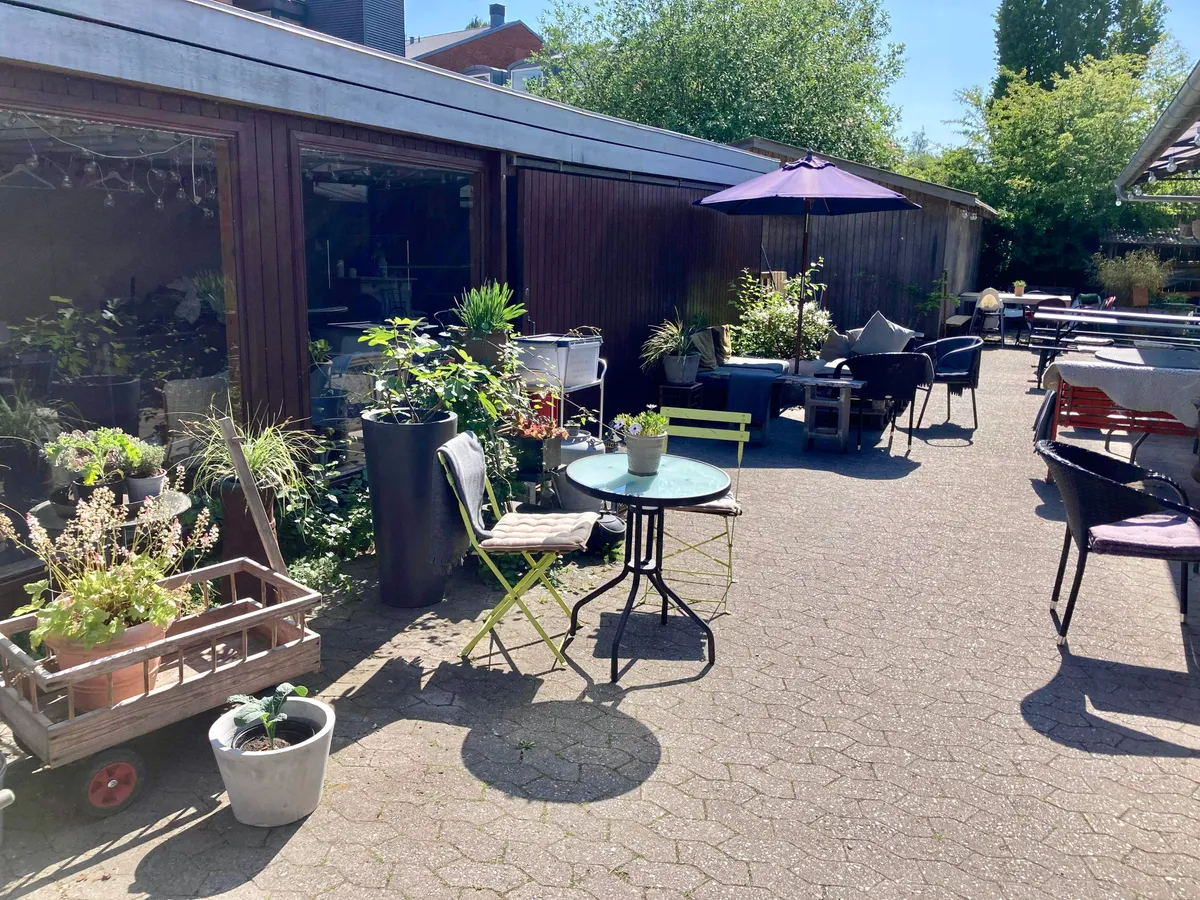 Kontor til leje med terrasse, hvor der er stole, en bord og paraply samt en række potter med planter