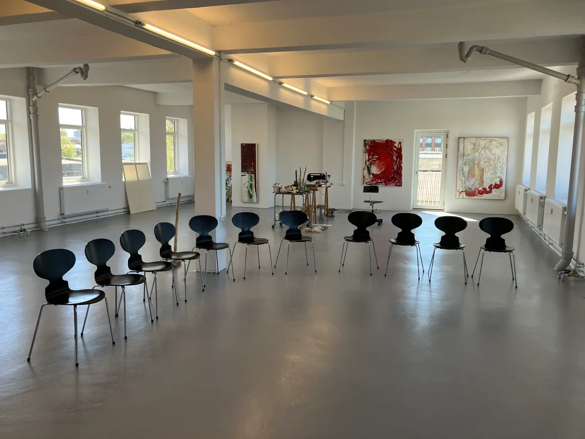 Kontorplads med mødelokaler til leje i Søborg. Anvendt er lyse gulve, hvide vægge, store vinduer og moderne møbler. Kunstværker og en åben dør til balkon.