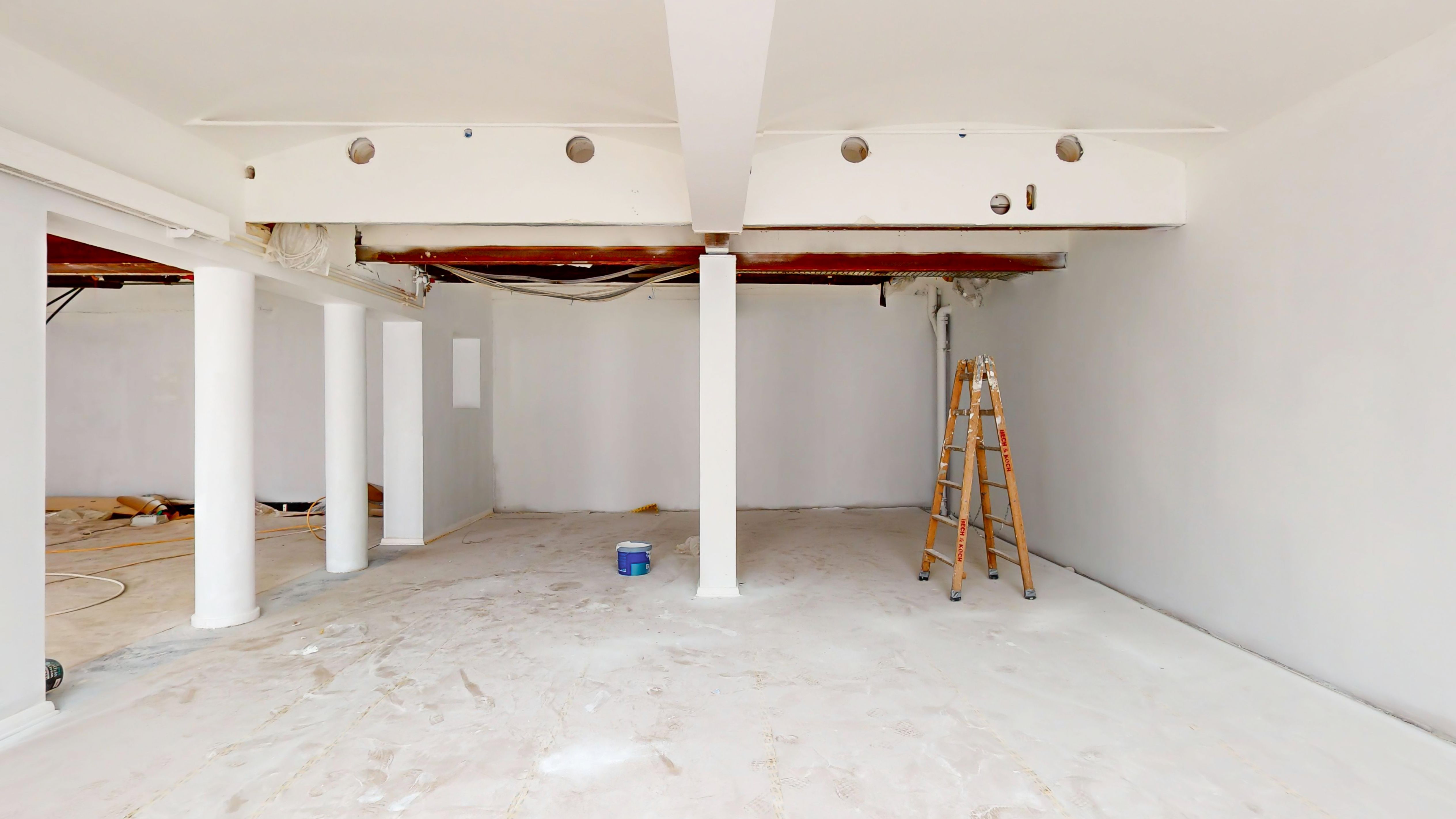 Ledig erhvervslejemål med højt loft, to kolonner og gulvbelægning. Plads til udstykning, vinduer og udstyr samt en stige.