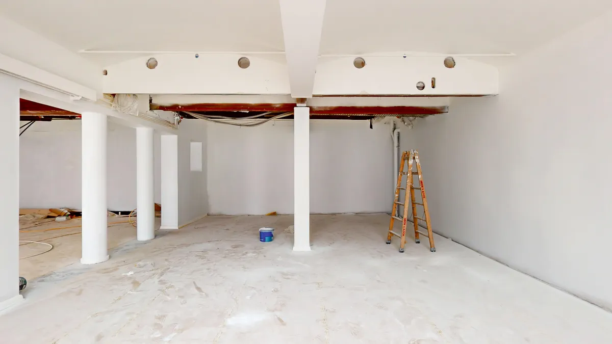 Ledig erhvervslejemål med højt loft, to kolonner og gulvbelægning. Plads til udstykning, vinduer og udstyr samt en stige.