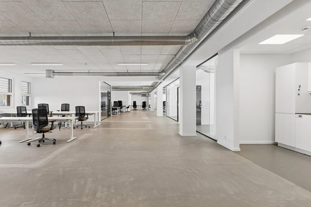 Moderne kontor med højt til loftet, hvide vægge og lyse lofter samt lysegulve og vinduer med gardiner