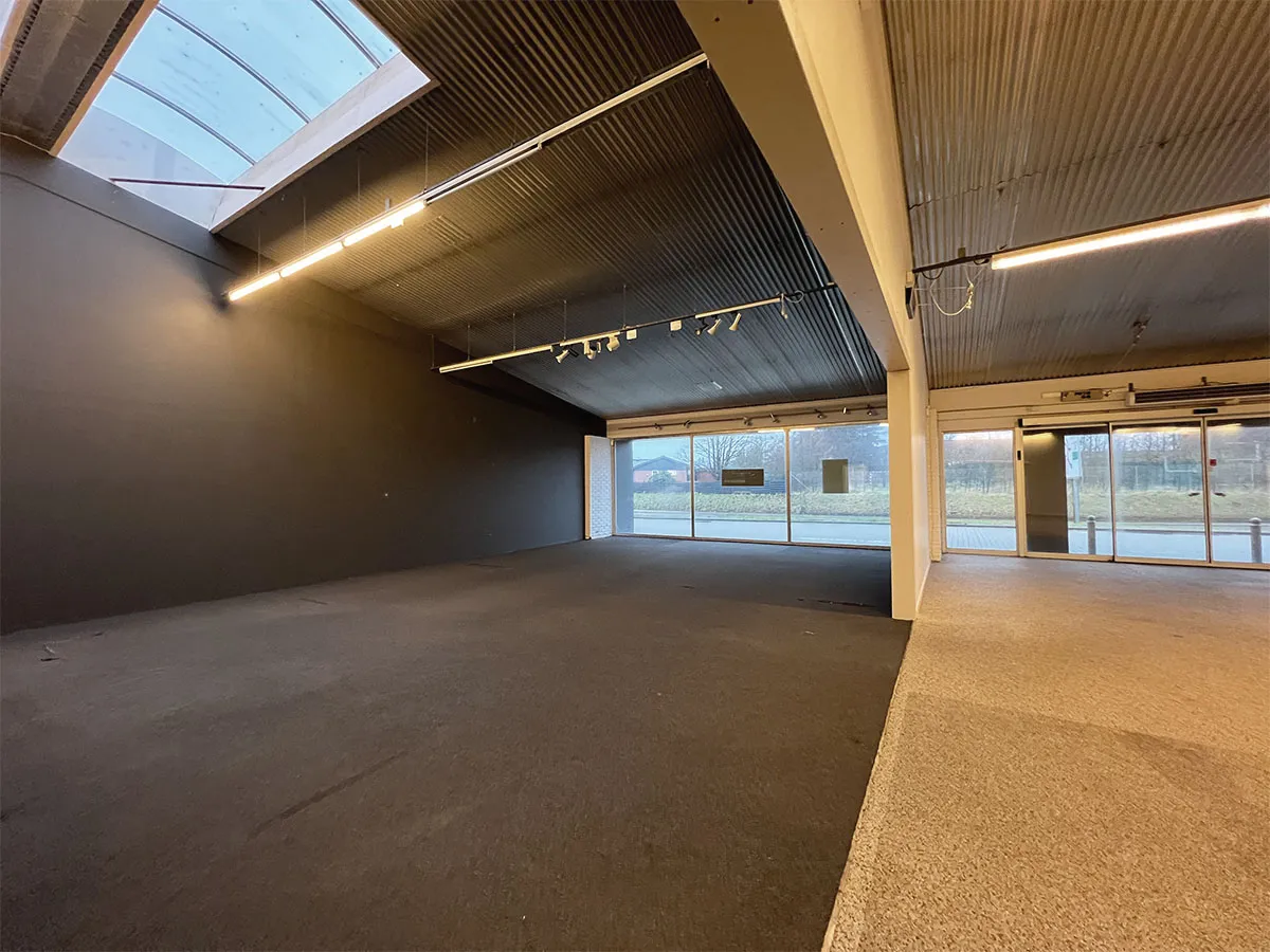 Lys og stor butikslokal til leje i Hjørring, med store glasruder, lys gulvbelægning og moderne loftsbelysning.