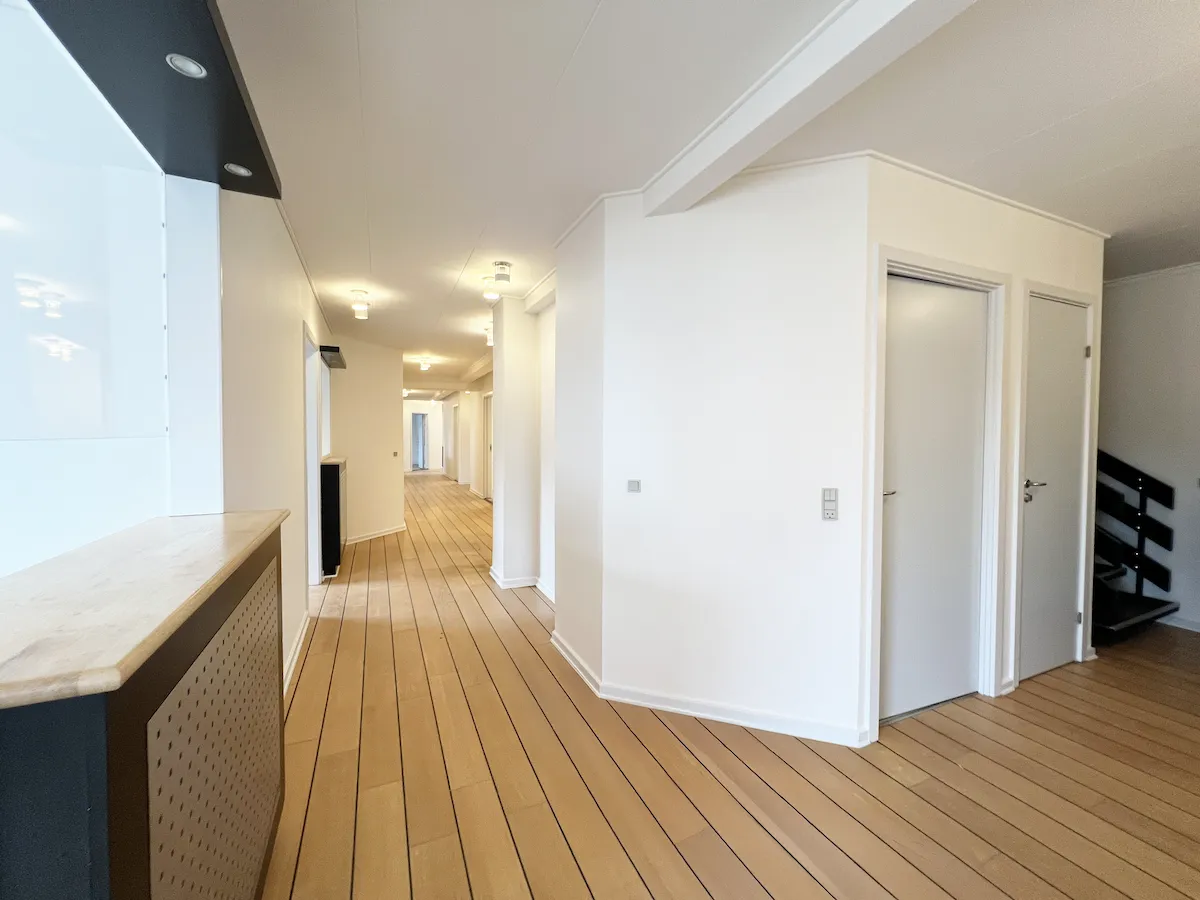 Lejet klinik i Hjørring med moderne interiør, åbne områder, hvide vægge, lyse lofter, lysekroner og lysepunkter, trægulve og døre
