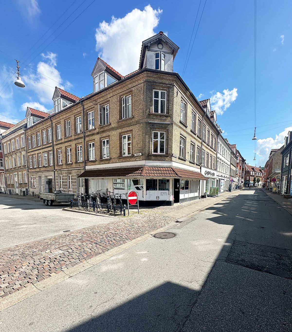 Lejlighed til leje i Aalborg, Reberbansgade 12A, 9000. Butik med mange vinduer og skrapelamper overfor. Mange cykler parkeret foran butikken