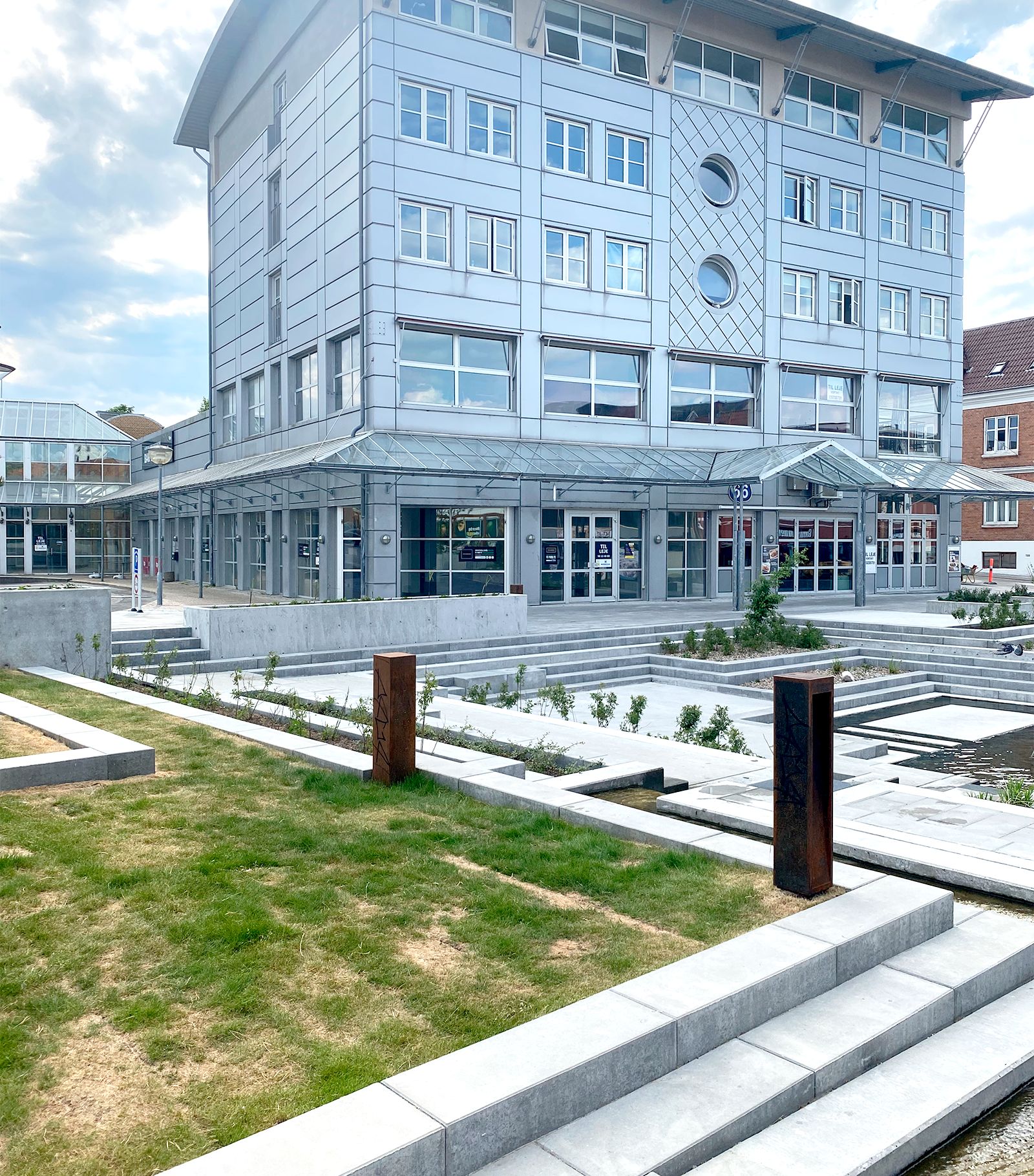 Bygningen med glas og metalfasade er placeret på Sct Olai Plads. Der er en stor entreplads med grønne anlæg og vand. Stiger og trapper fører til bygningens indgang.