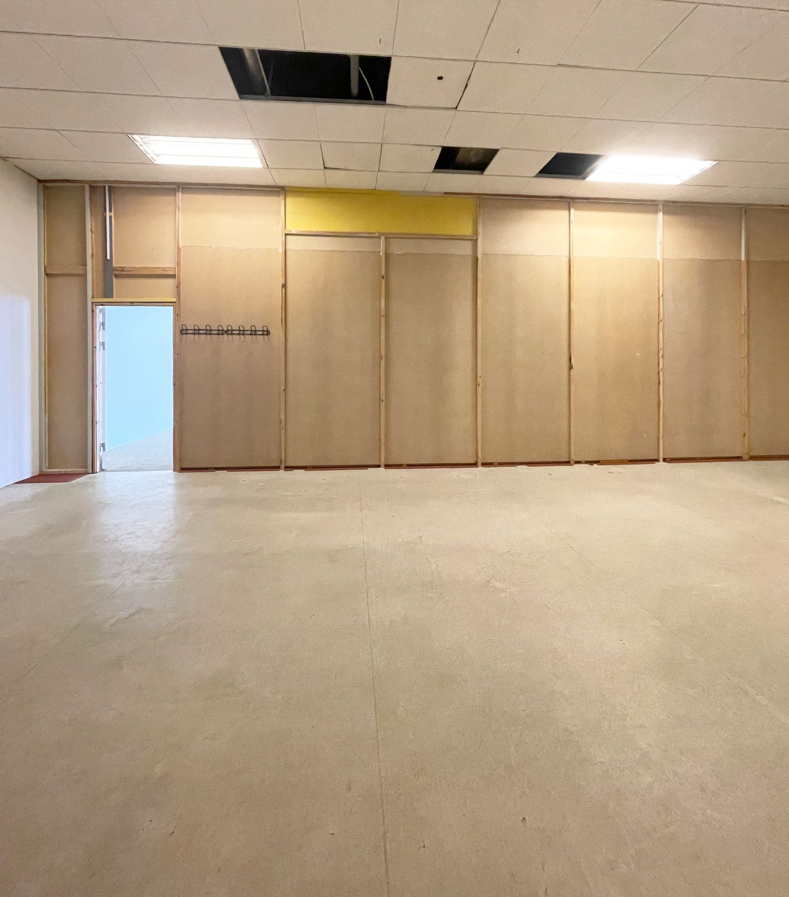 Store butikslokaler med højt loft og lyse gulve og vægge. Der er udvendigt en dør og indvendigt er der en nyindrettet væg med et nyt loftssystem.