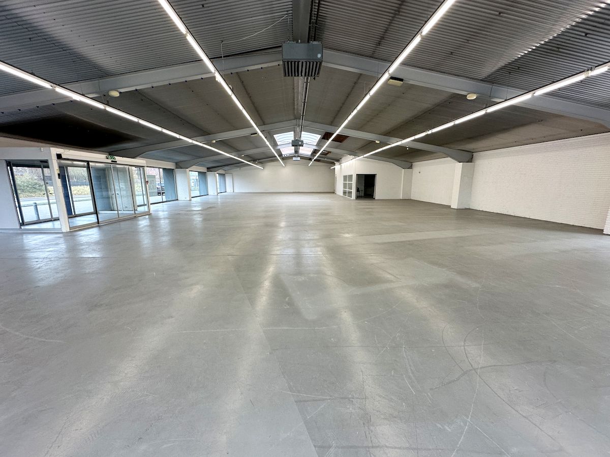 En stor, tom bygning med store vinduer og lyse loftsbjælke, der er velegnet til en virksomhed med store behov for plads og synlighed