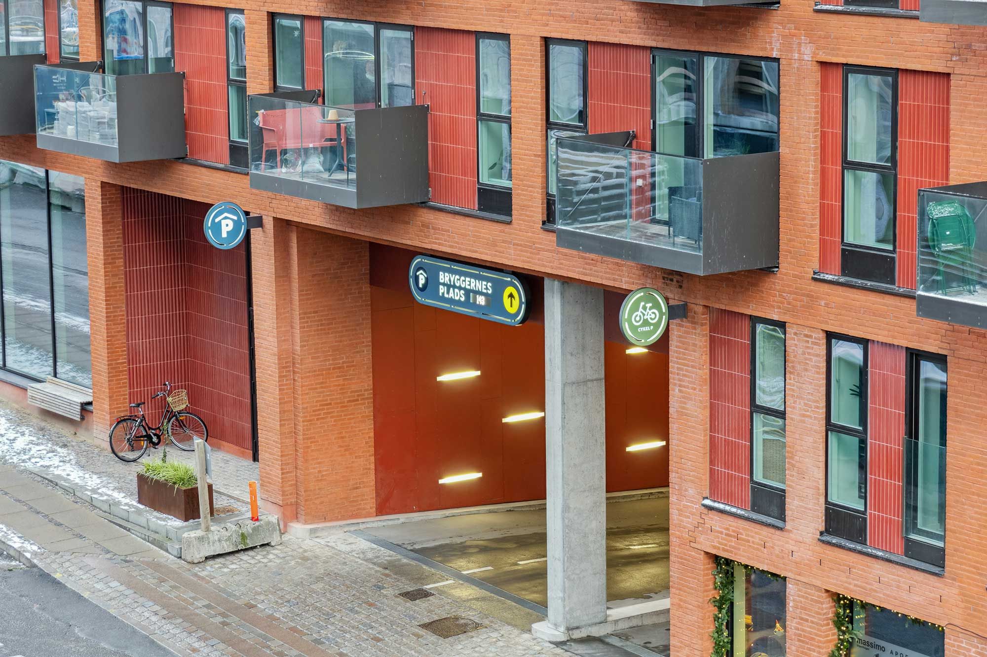 Kontorlejemål i Carlsberg Byen med garageindkørsel og terrasser med redskaber og stole, gul vejvisning og grøn cykelskilt