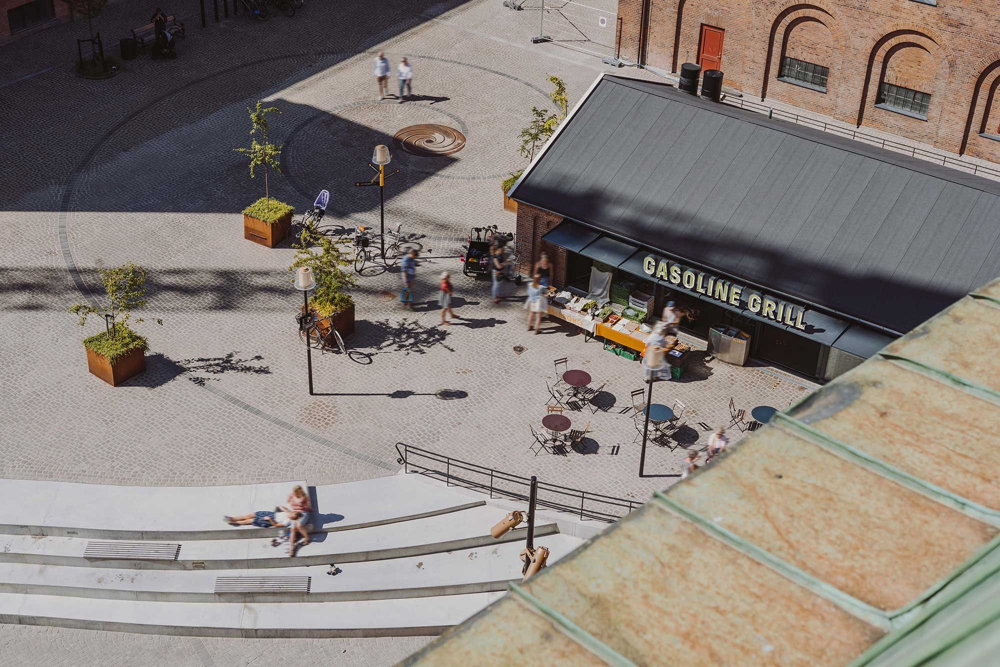 Råt og højloftet kontorlejemål i Carlsberg Byen med udsigt til Bryggernes Plads og J. C. Jacobsens Gade med restaurant og gæster