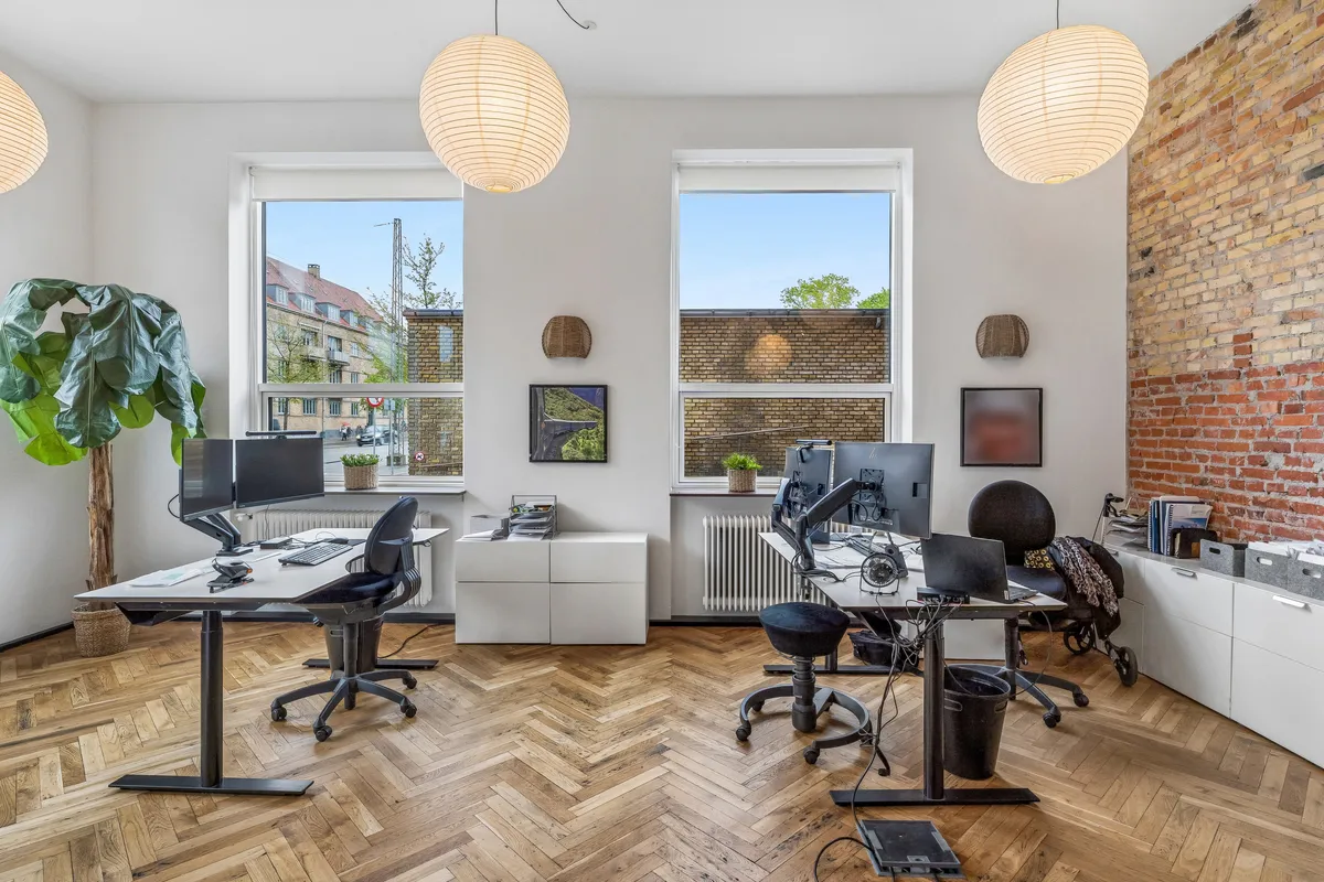 Kontor med trægulve og lyse vinduer. Værelser med højteknologiske skriveborde og stole. Planter og vægdekorationer forbedrer kontorens atmosfære. Moderne møbler og teknologi.