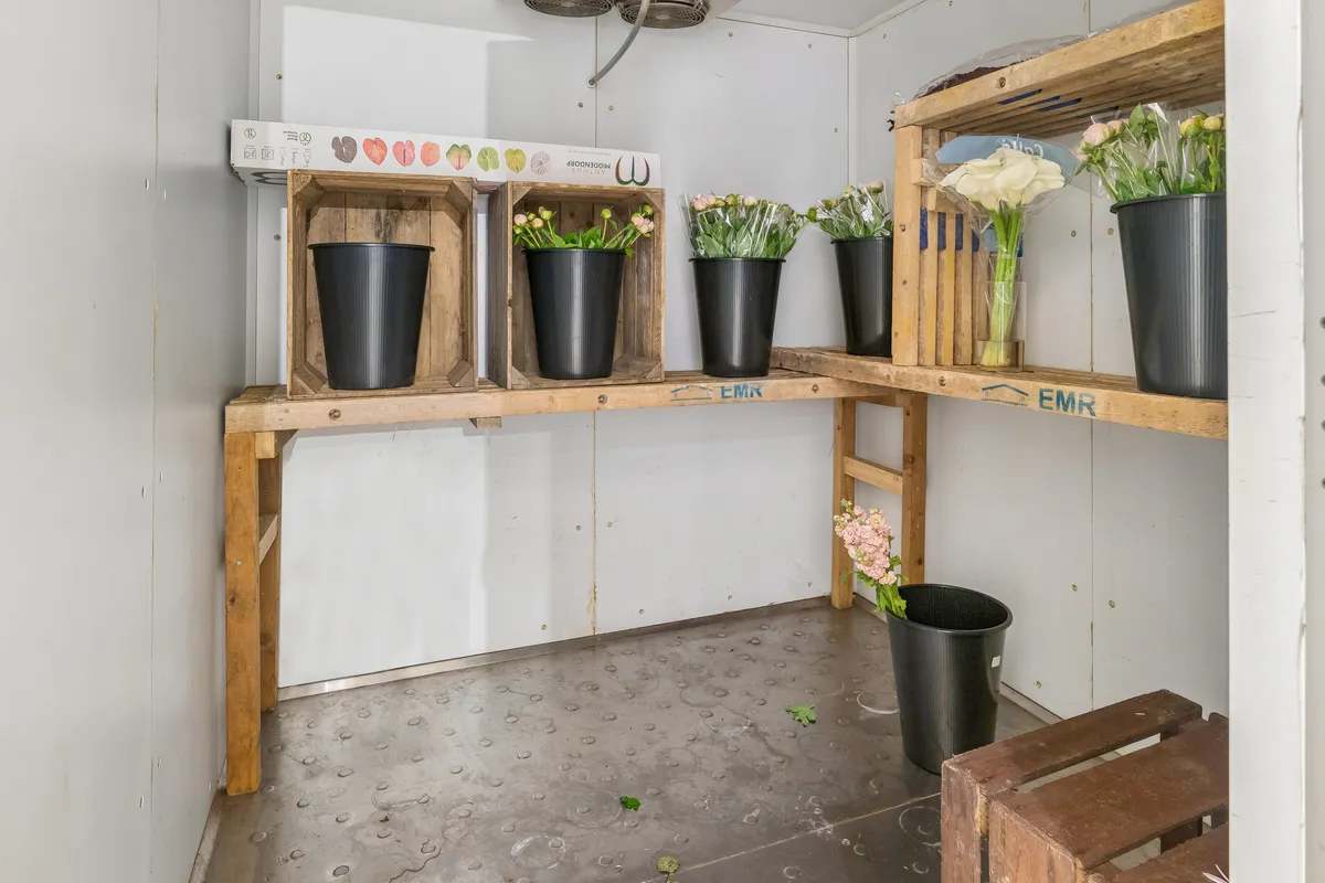 Lejlighed med blomsterbutik. Blomster i vase og kasserne med blomster og kartoner med blomster i butikken.