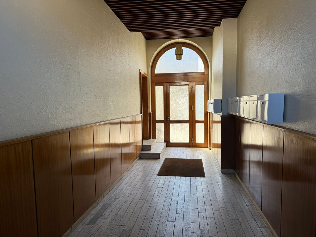 Elegant og stilfuldt kontor med højloftede lokaler og møbleret gulv. Et slankt, glasdækket vindue og lyse lofter. Værelser med træbeklædte vægge og trægulv.