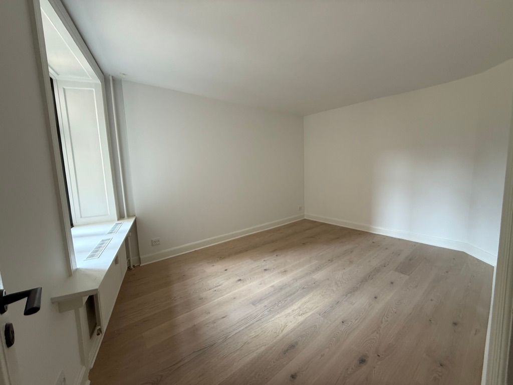 Kontor til leje på Nørre Farimagsgade 37, st. 1364 København K med højloft og lyse trægulve. Et afslappende værelse med hvide vægge og en komfortabel vindueskarm.