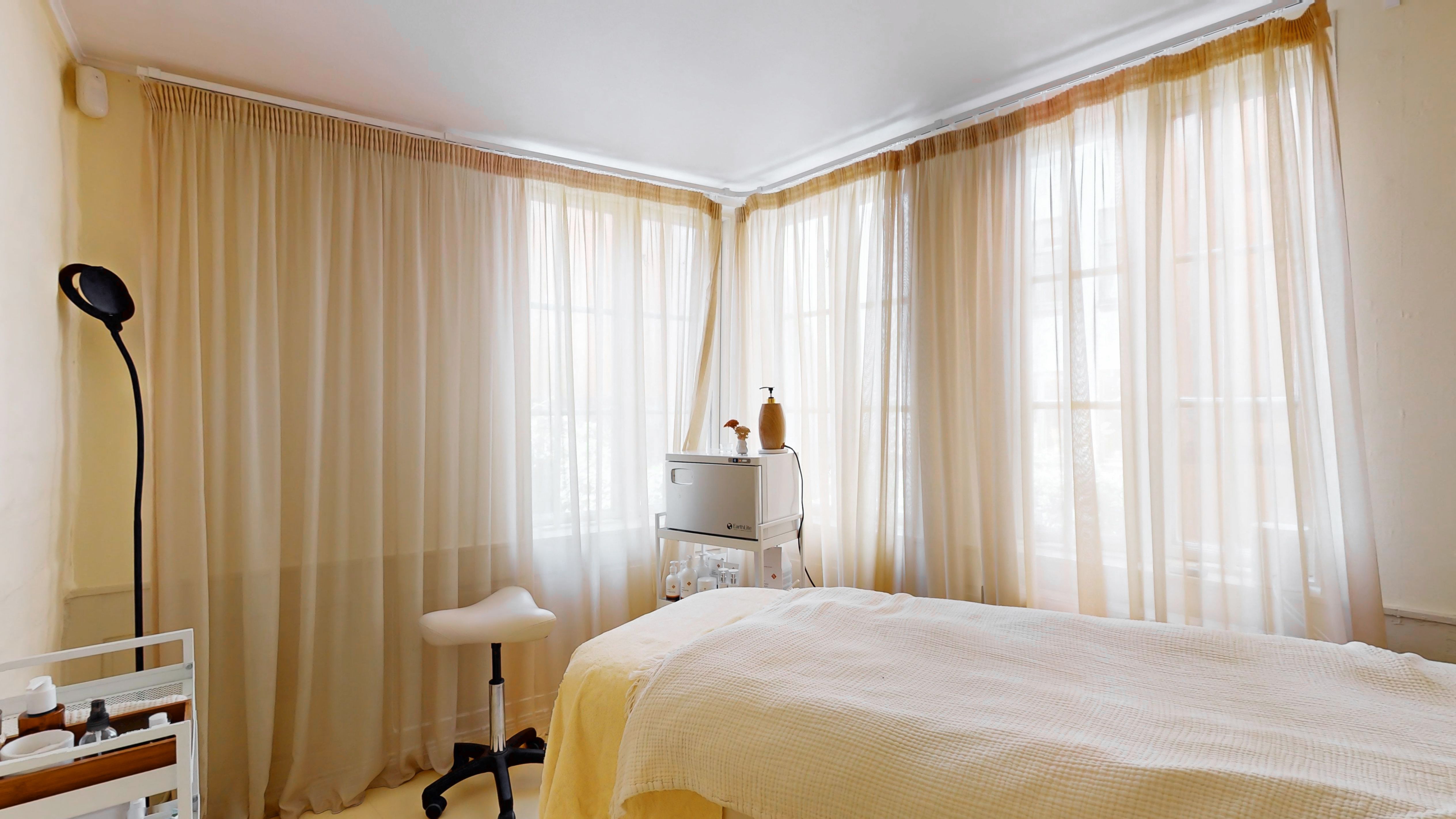 På massageværelse med massagestol og massagebord med cremeflasker og håndcreme.