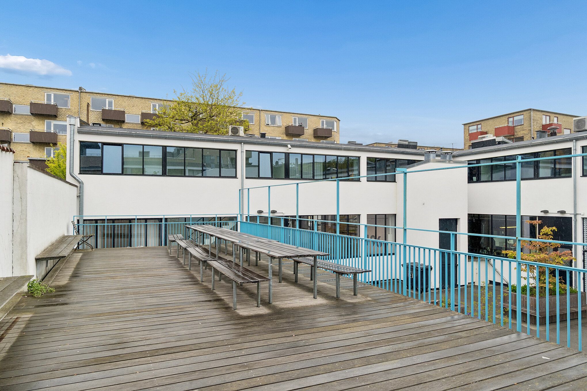 Karakterfuldt kontorlejemål med terrasse, bænke og en lang bord på gården i København NV