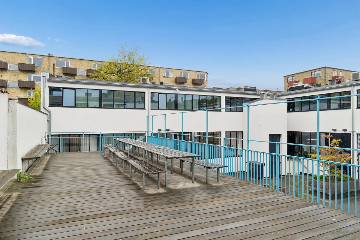 Karakterfuldt kontorlejemål med terrasse, bænke og en lang bord på gården i København NV