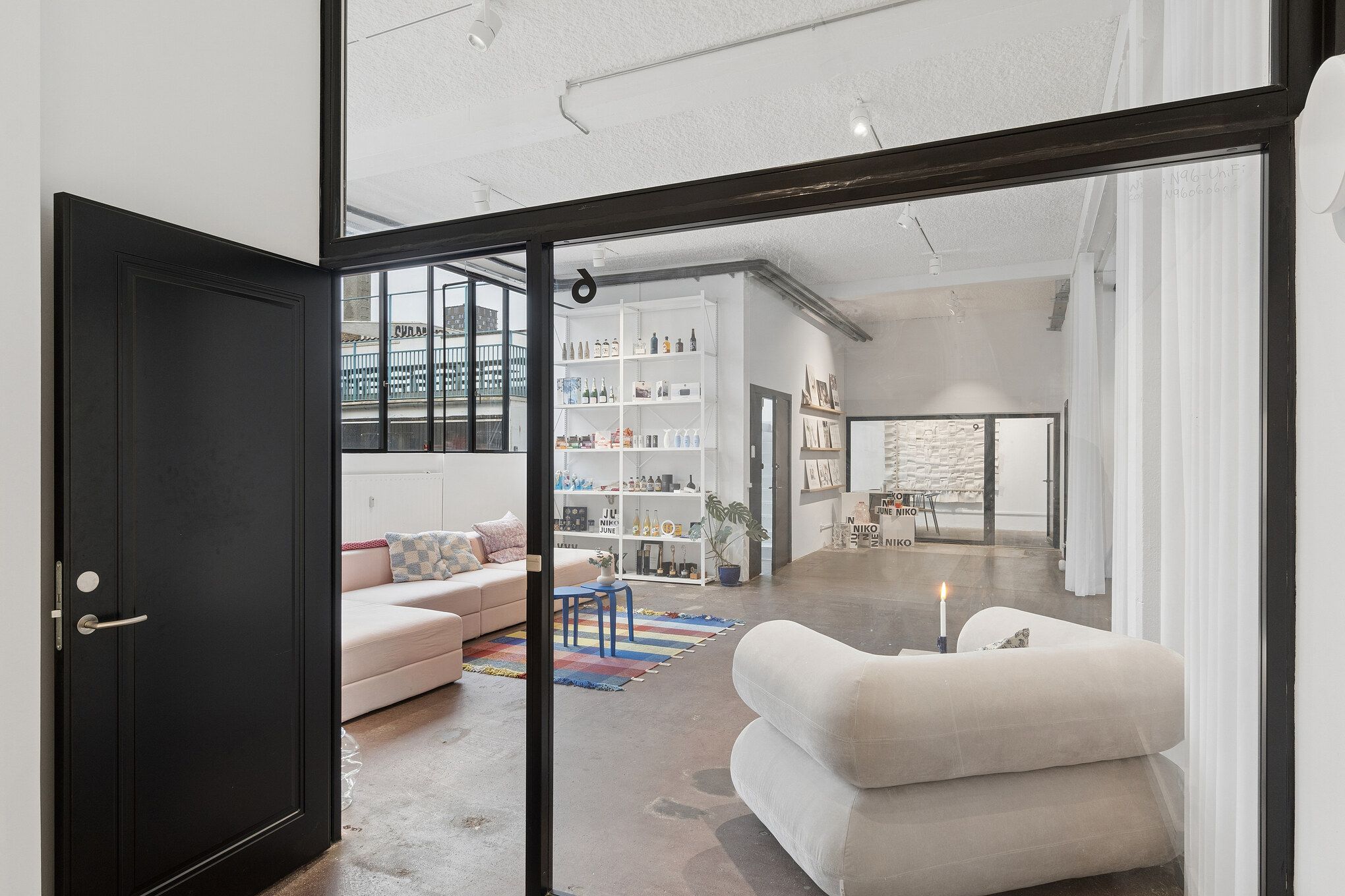 Kontor med åben og fleksibel planløsning, stor sofa, bord med lyse puder og lyse vinduer mod gården