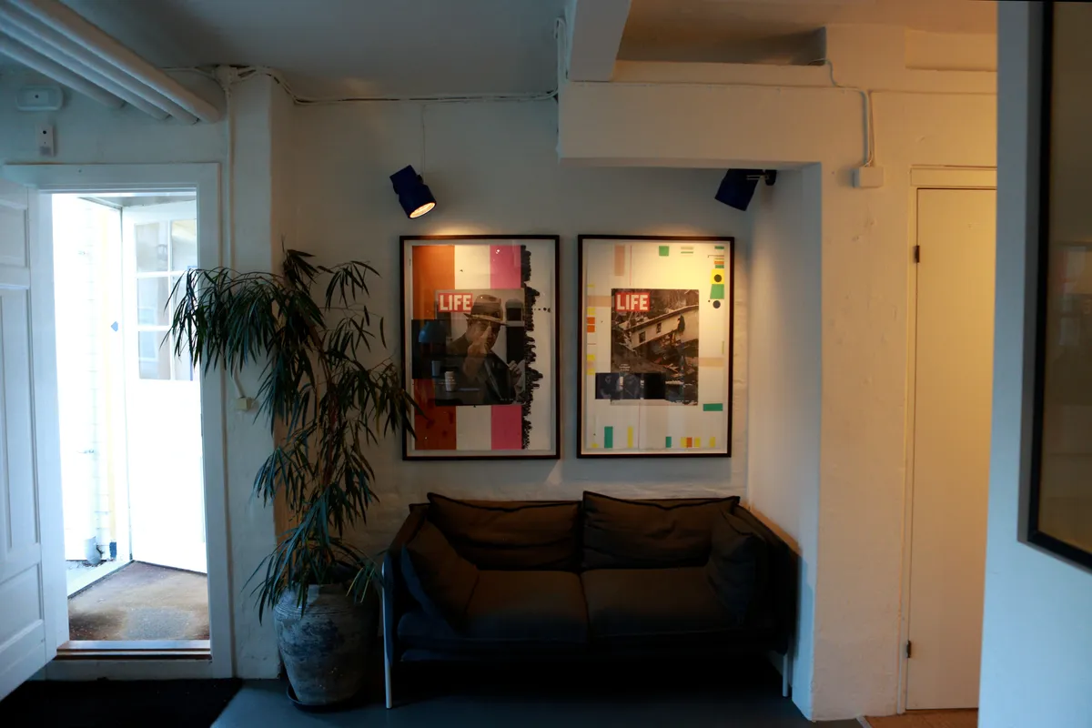 Sofa i stuen med to lysekroner i loftet og to malerier med teksten "Life" i højre væg