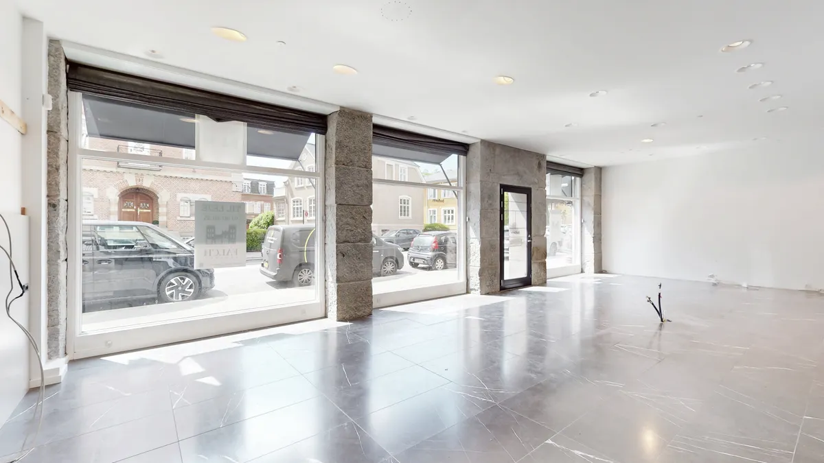 En stor, glas- og stenklædt facade med store vinduer og møblerne og det lyse loft.