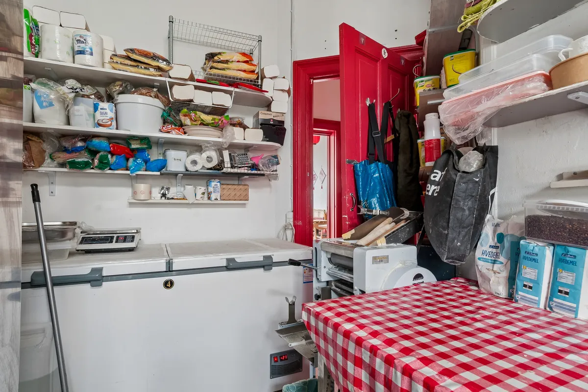 Bagerlokal med køleskab, varmeapparat, skabe med hylder, bøfsandwicher, emballage og flere genstande og ingredienser til bagning og madlavning