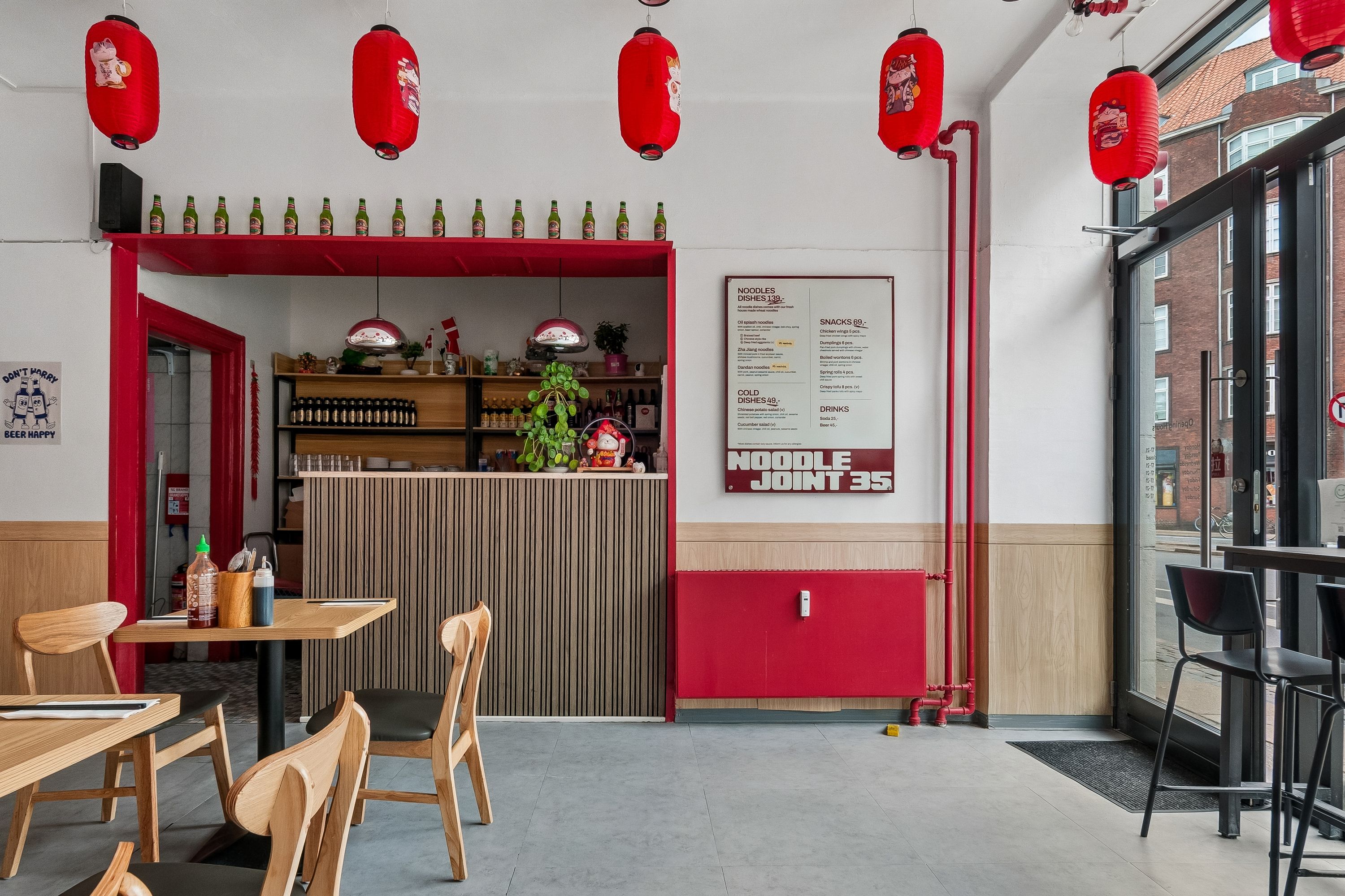 Godt møblet restaurant med moderne spisestue og bar. Asiatisk udsmykning med røde lanterner og menu på væggen. Sorte og brune stole samt træborde.