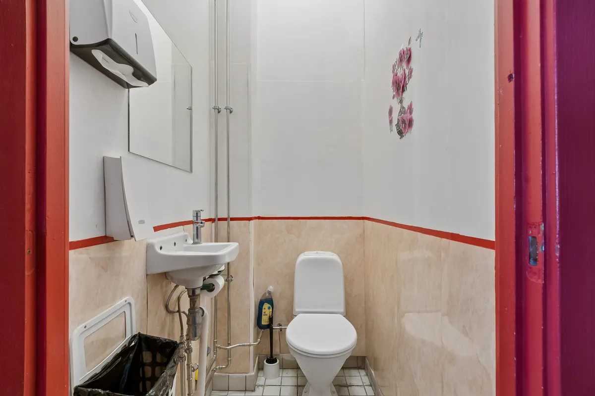 Alt tekst: Toilet med høj kvalitet og hygiejne. Hvid toilet med papirhåndklædeautomat og en ren toiletbørste.