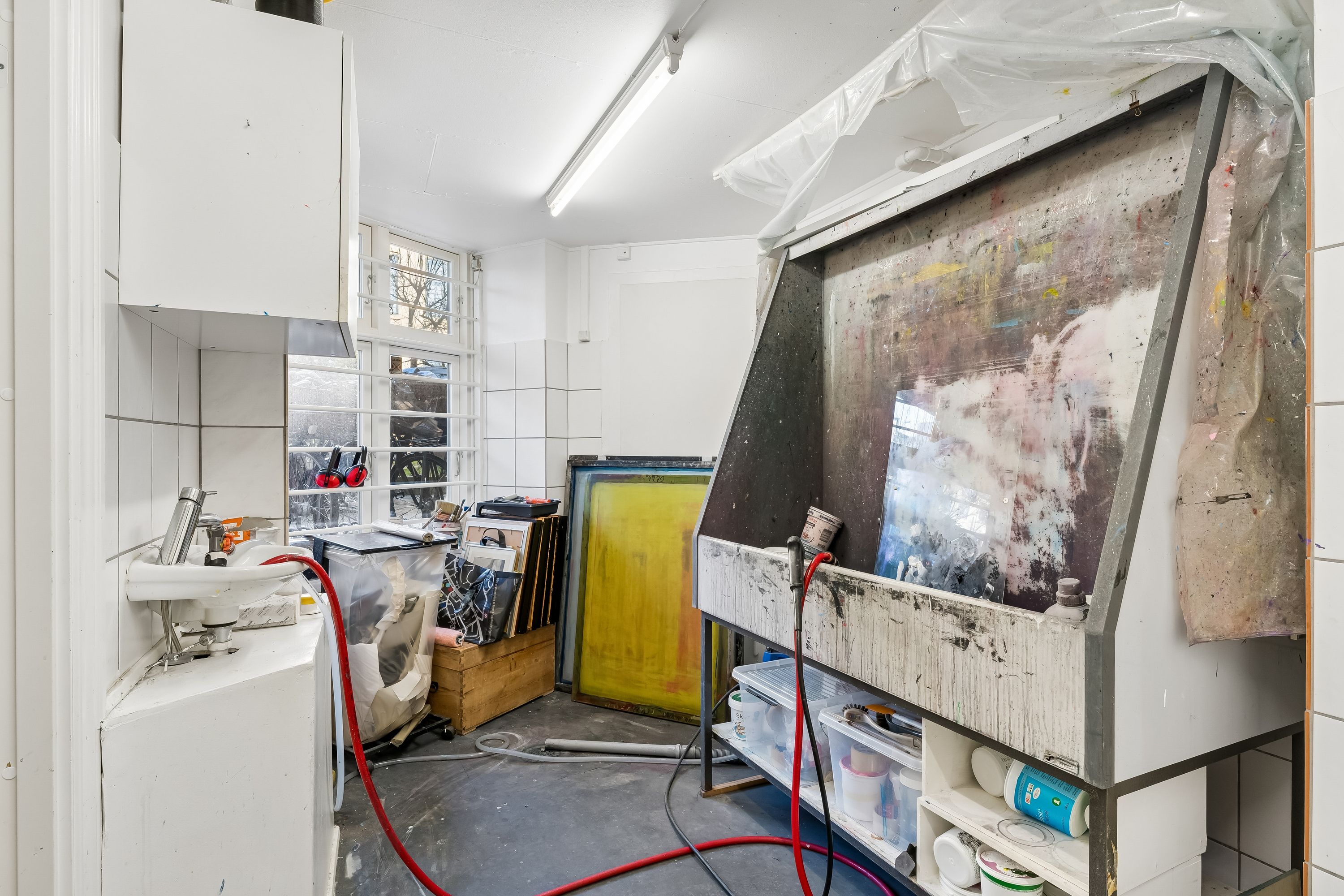 Malerværksted med værktøj og materialer, gulv vask, spraykabine, malerstavne og flere malerfarver