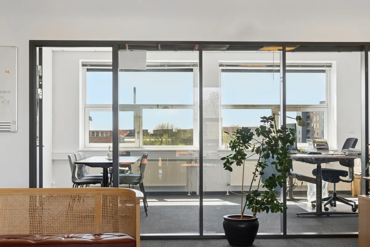 Kontor med masser af lysindfald og møbler som bord, stol og plante, samt vindue og dør til leje i Glostrup