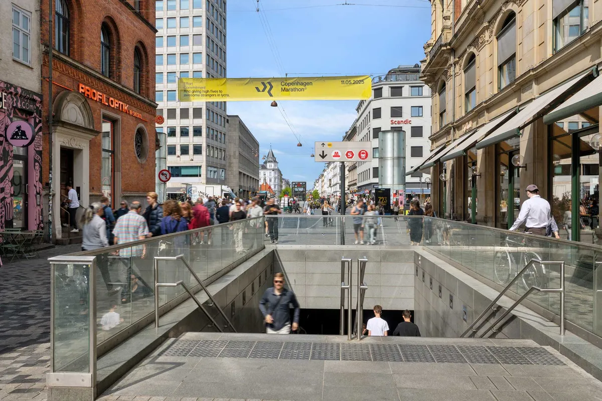 En kontorets indgang med glas trapper og håndtag, en mand med cykel, mange mennesker og bygninger med reklamebanners og skilte