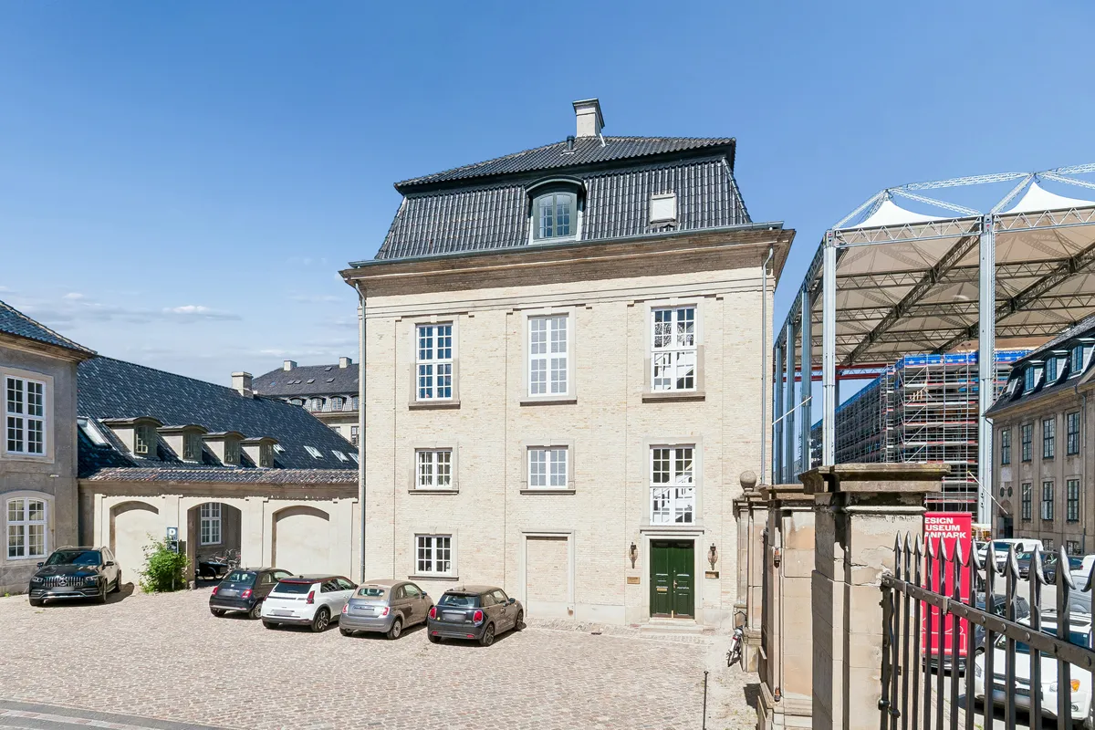 På Amaliegade 31A parkerer flere biler foran og bag en husleje med flere vinduer og en grøn dør. En stang med rødt skilt står på hjørnet
