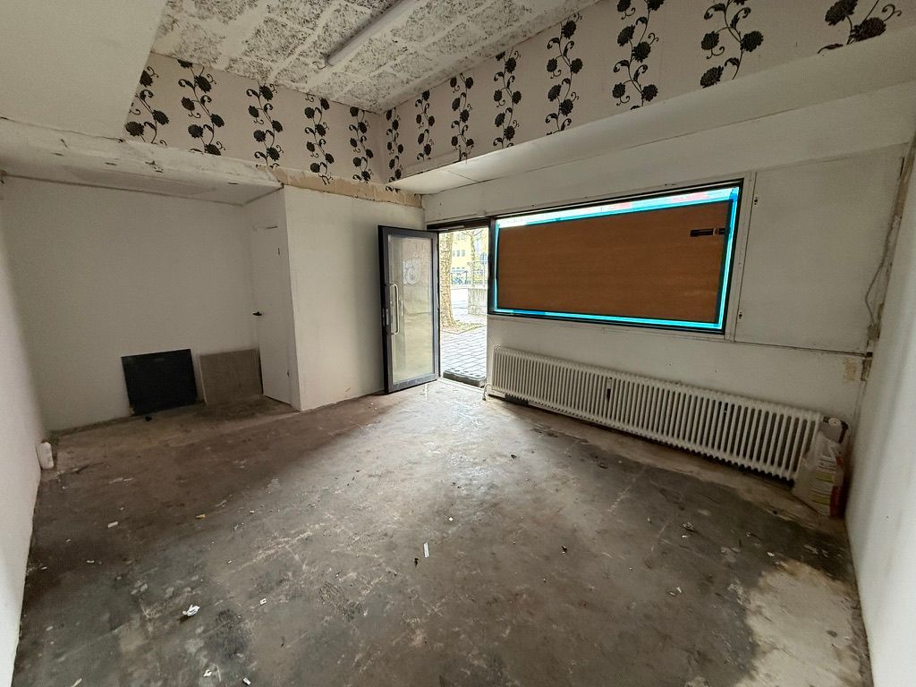 Butik med forretningslokaler og lagerplads til leje i Kongens Lyngby. Værelser med hvide vægge og lofter og en dør til butikken.